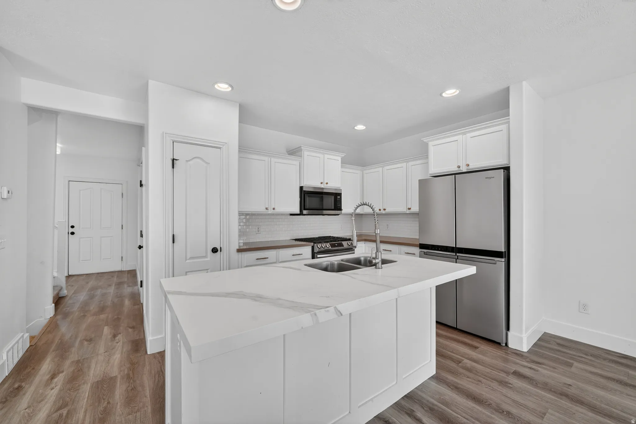 Kitchen island featuring a dual-basin sink and a light-toned countertop with veining