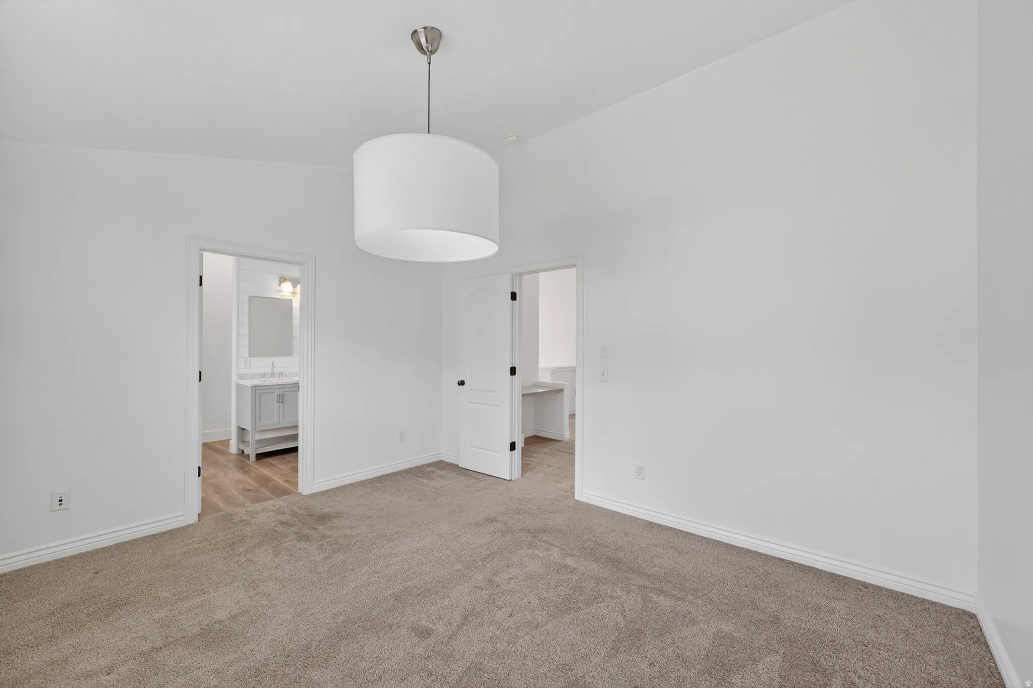 Spacious room with plush carpeting, crisp white walls, and a contemporary drum pendant light fixture