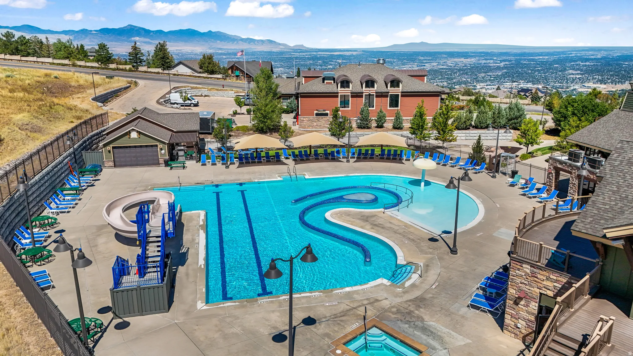 Expansive outdoor swimming complex featuring multiple pools, a water slide, and a separate hot tub