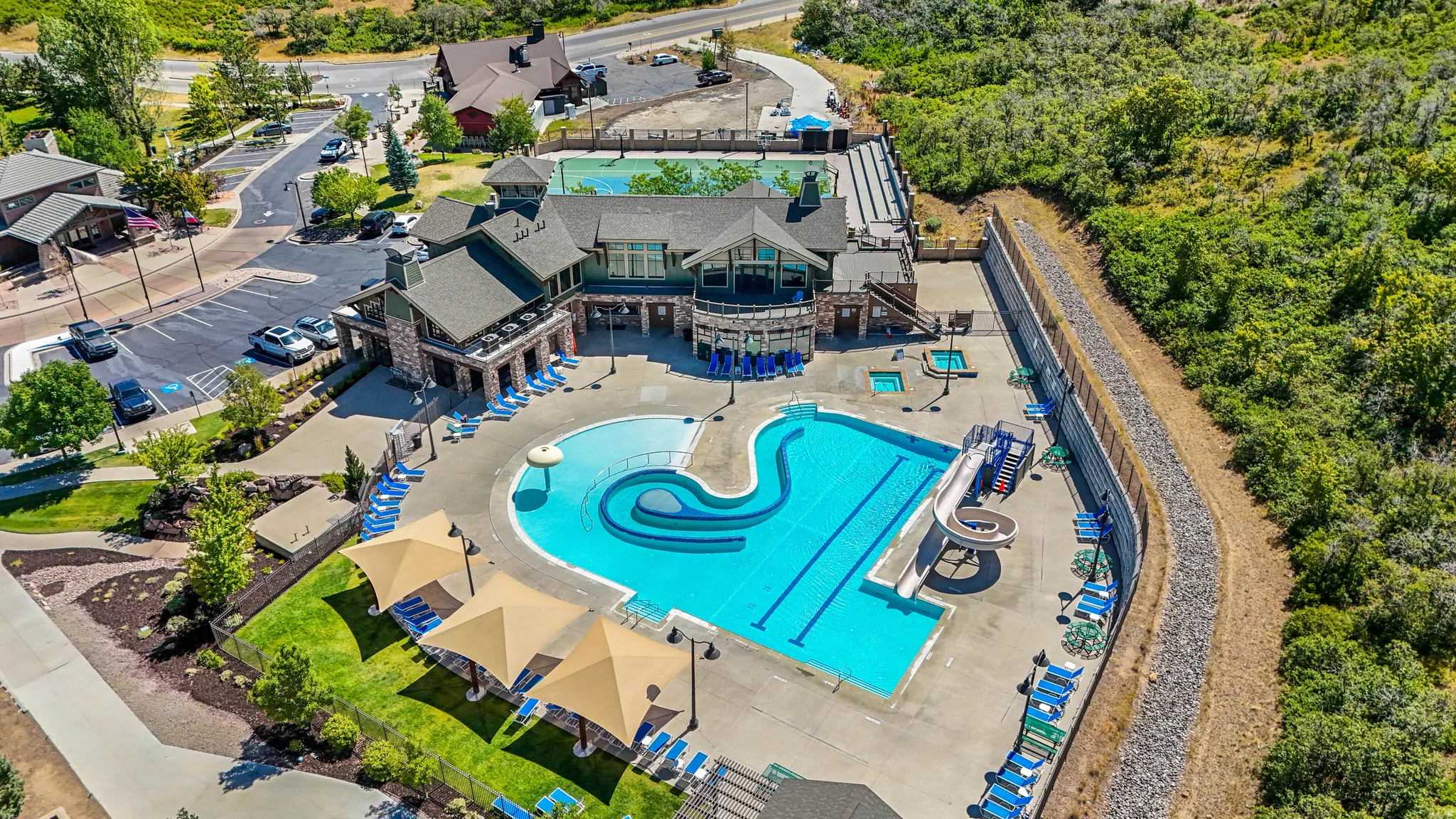 Resort-style pool area featuring a large swimming pool with distinct activity zones, multiple hot tubs, and a water slide