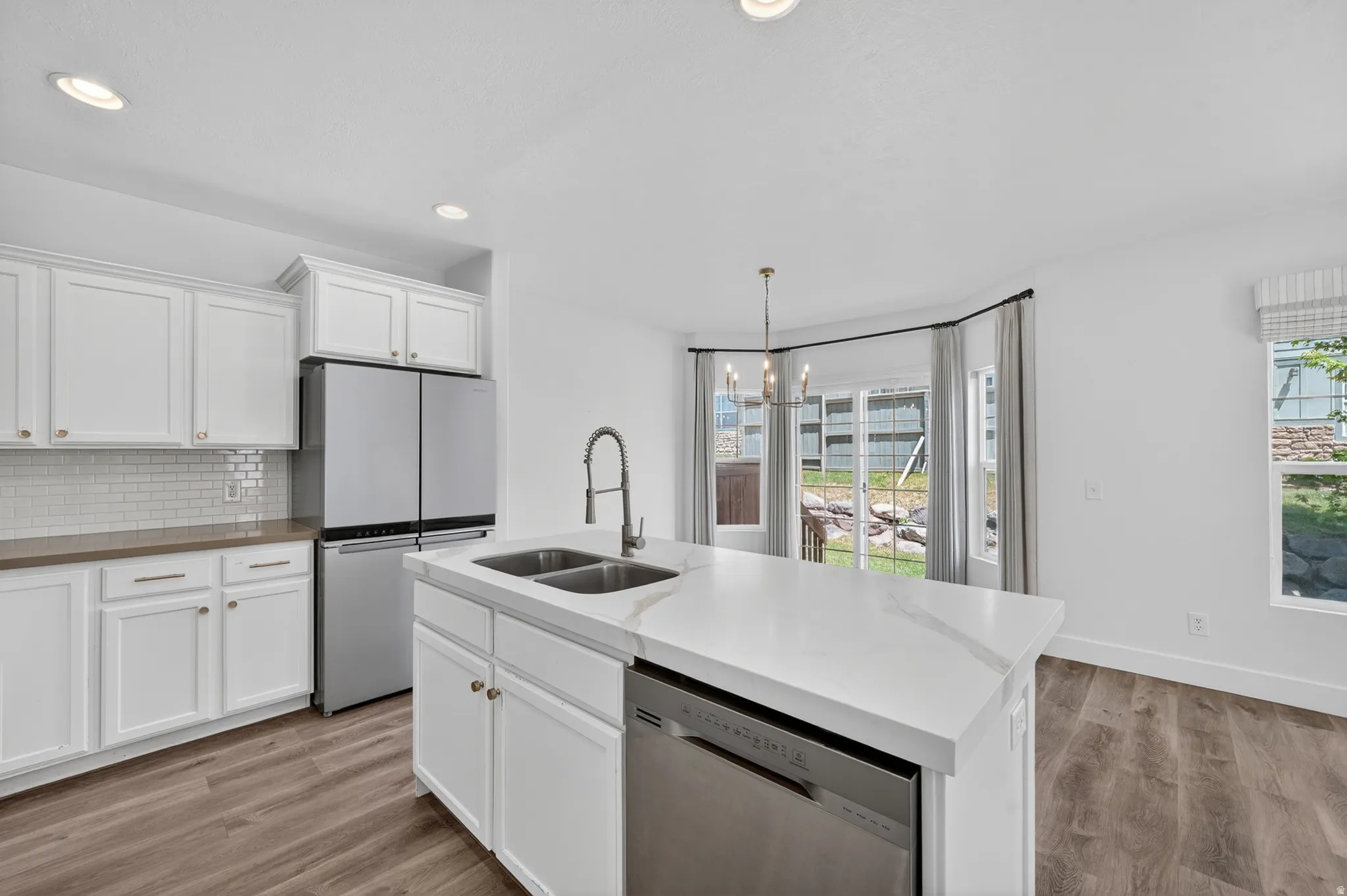 Modern kitchen featuring white cabinetry, stainless steel appliances, and wood-finish flooring