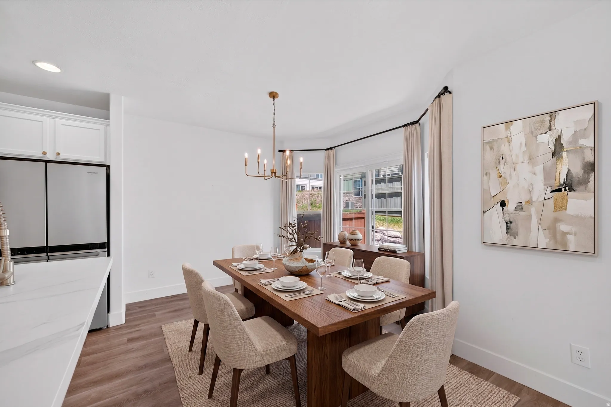 Bright dining area featuring a bay window, wood-finish flooring, and a modern chandelier