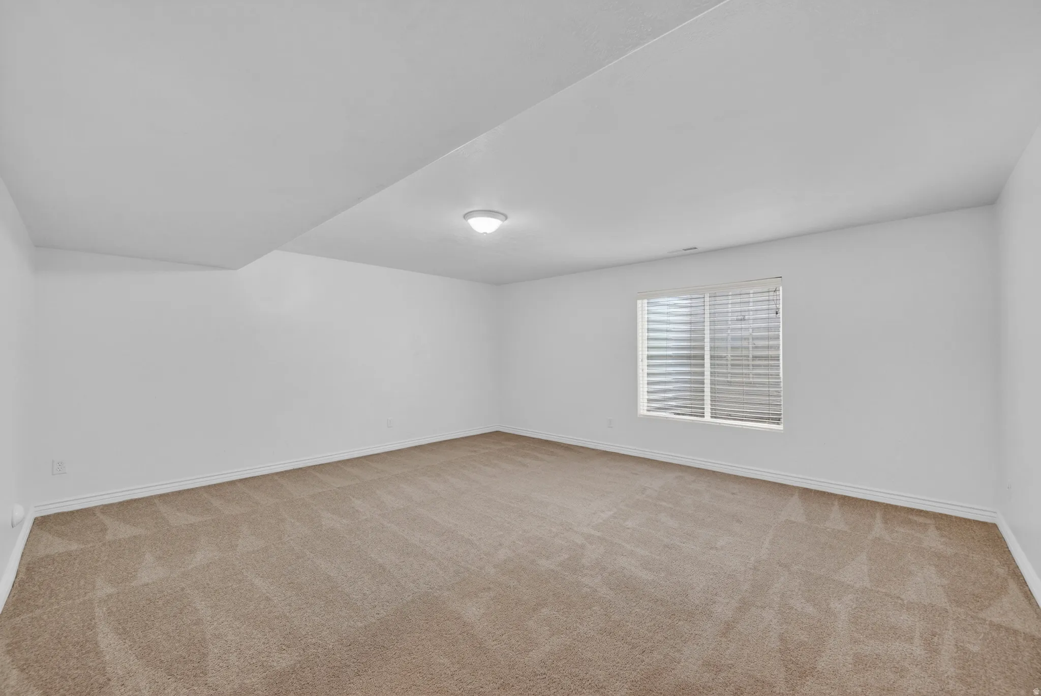 Spacious room featuring neutral carpet flooring and freshly painted white walls