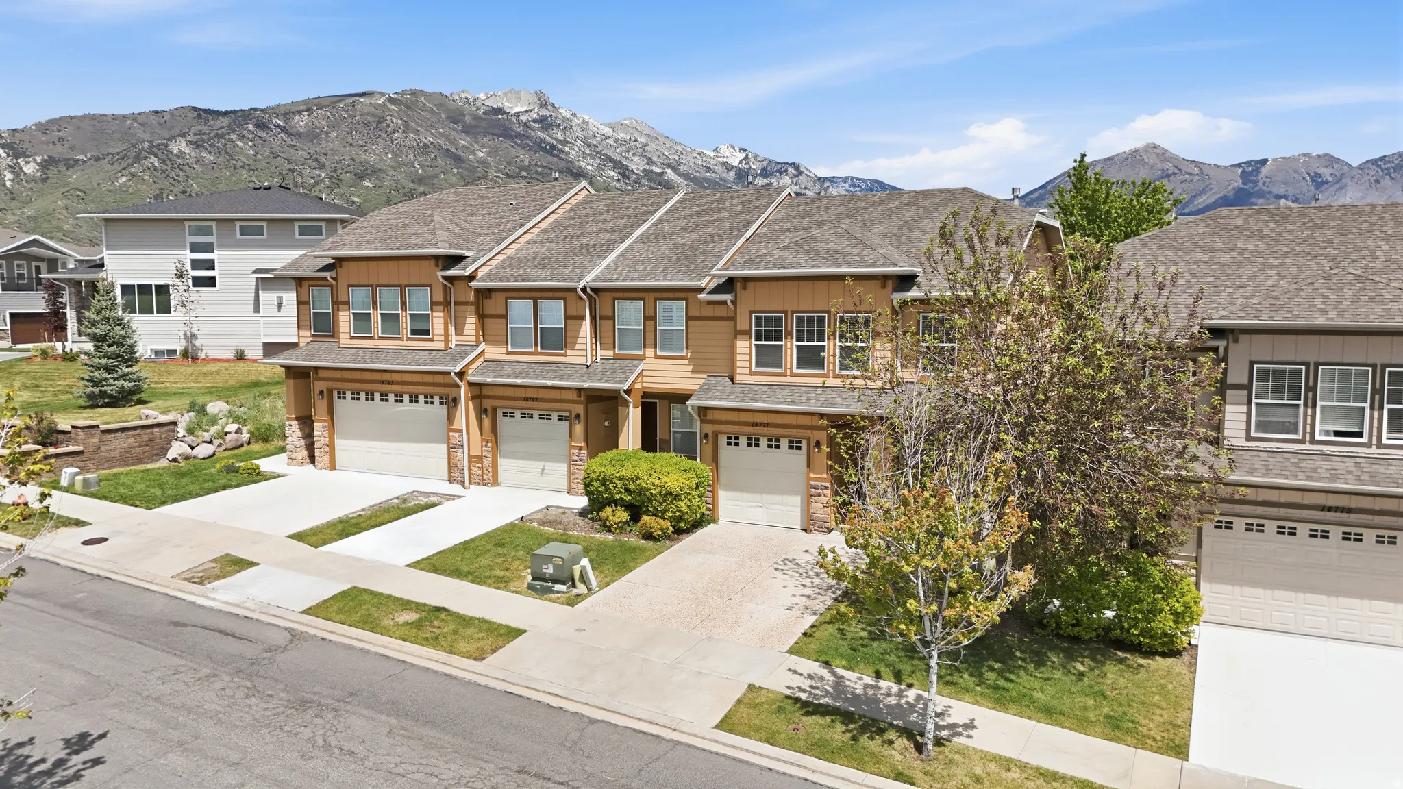 Contemporary townhome residences featuring multi-car garages, light wood-finish siding, and durable shingle roofing
