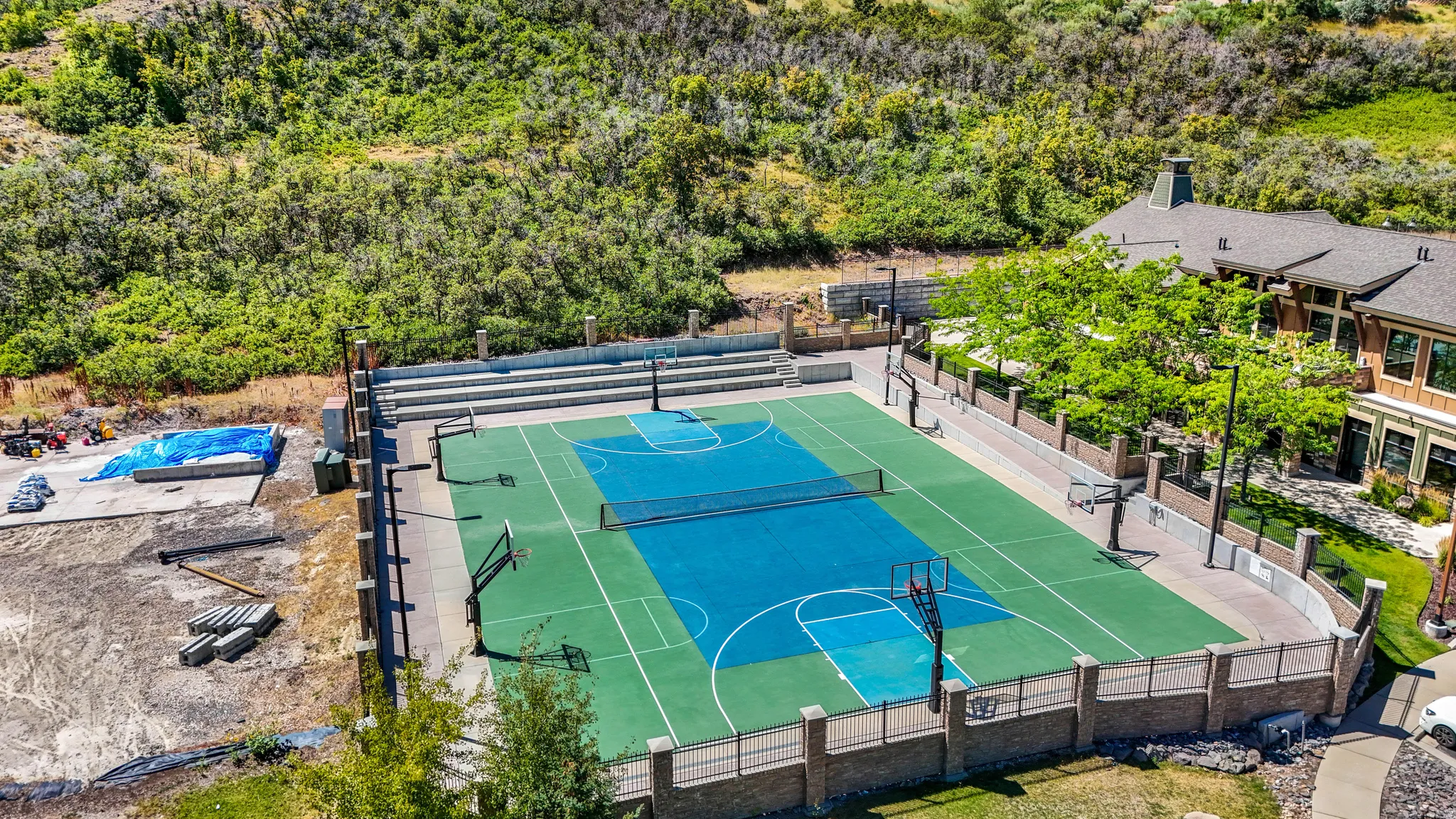 Multi-sport court featuring a vibrant blue and green surface, complete with basketball hoops and a tennis net