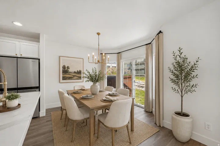 Open concept dining area with wood-finish flooring, white cabinetry, and stainless steel appliances