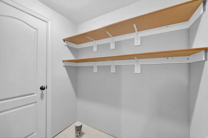 Corner shelving unit featuring two levels of wood-finish shelving with white brackets