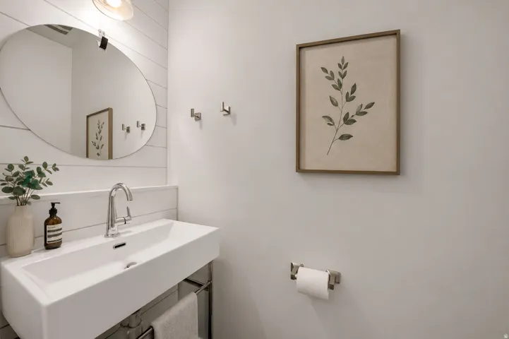 Wall-mounted rectangular sink with chrome faucet, oval mirror, and shiplap accent wall