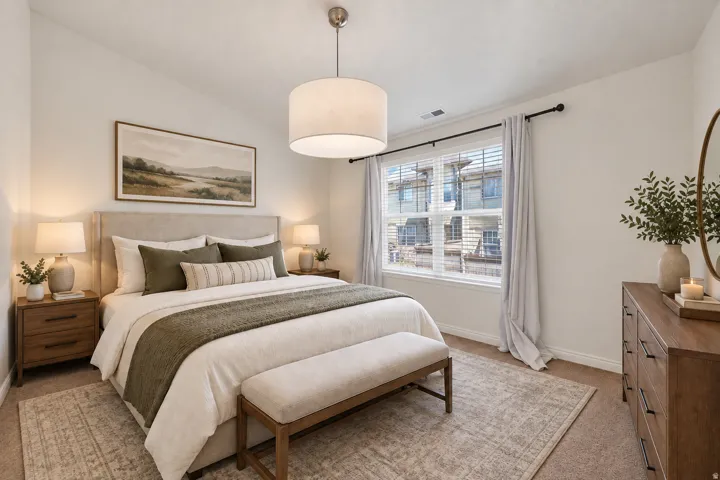 Carpeted bedroom featuring a large window, a drum pendant light, and an upholstered headboard