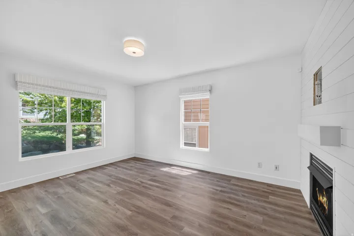 Spacious room featuring wood-finish flooring, white baseboards, and a fireplace with a white shiplap surround