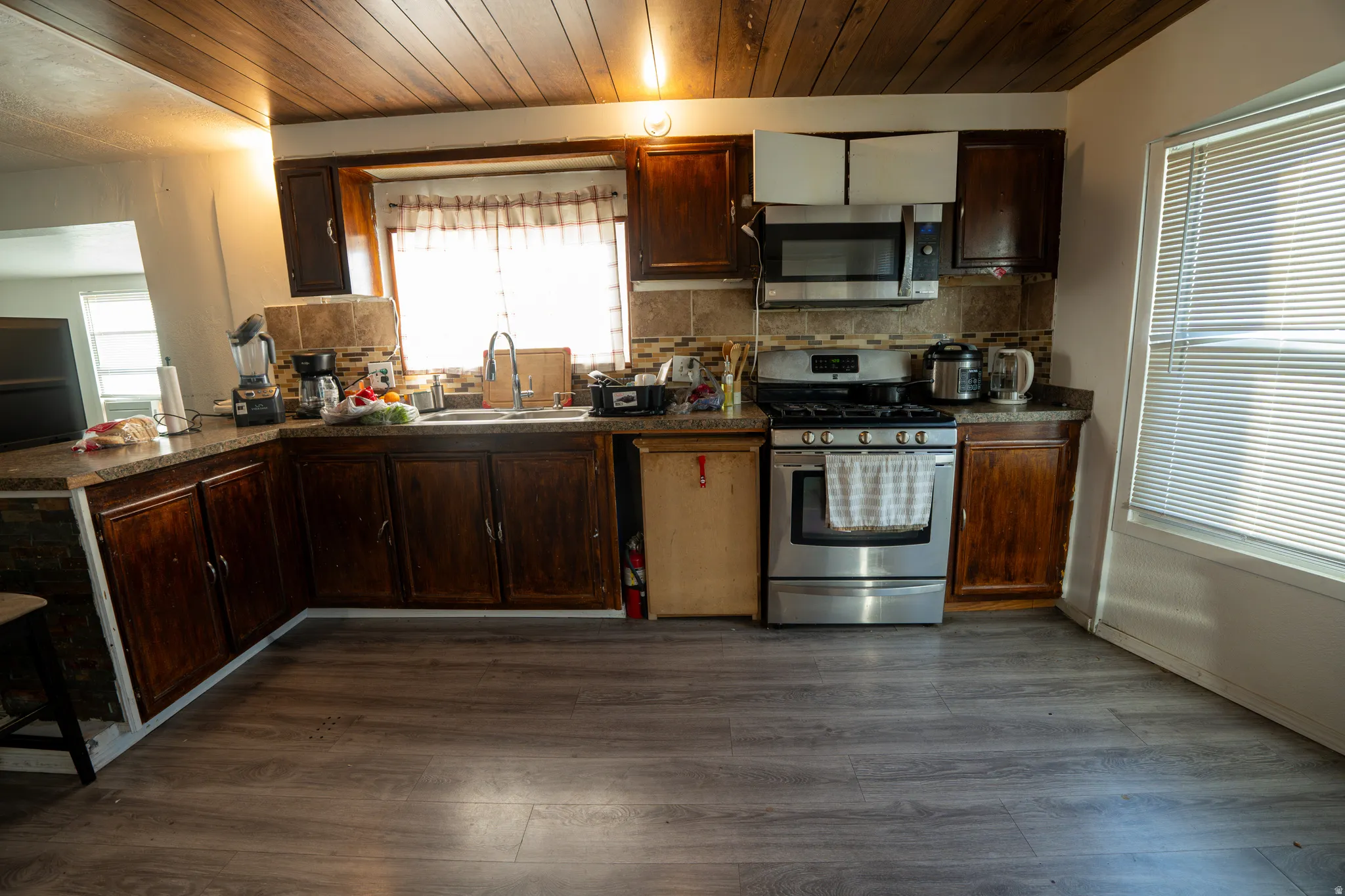 Kitchen featuring wood-finish flooring, dark wood cabinetry, and stainless steel appliances