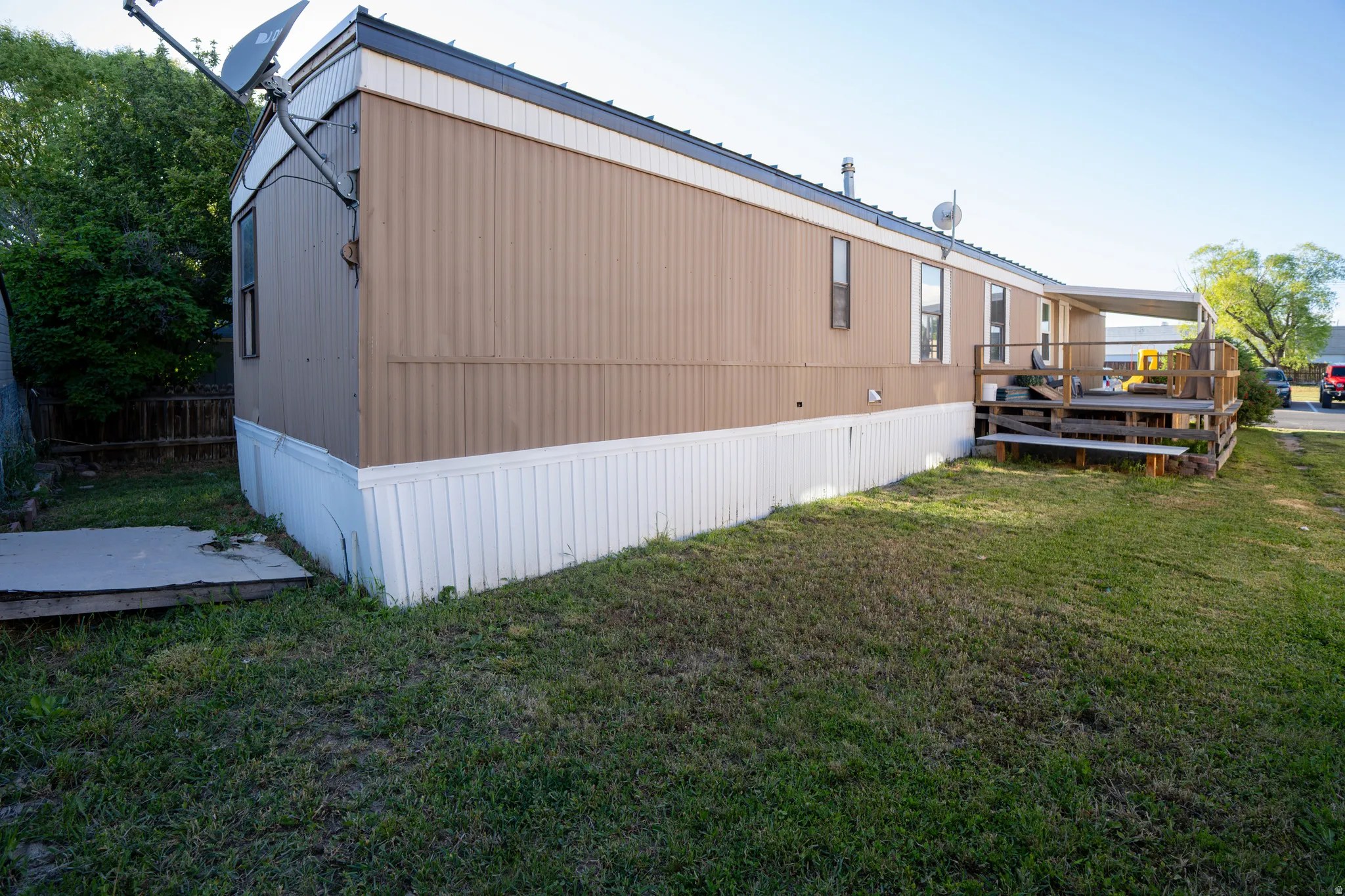 Exterior showcasing tan siding, white skirting, and a dark trim roof