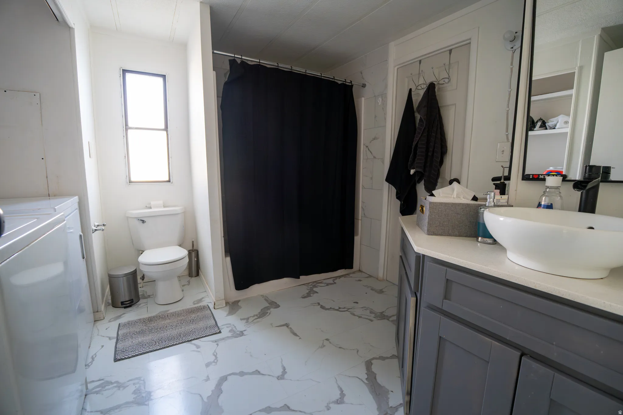 Bathroom featuring a vessel sink atop a gray vanity with a light-colored countertop