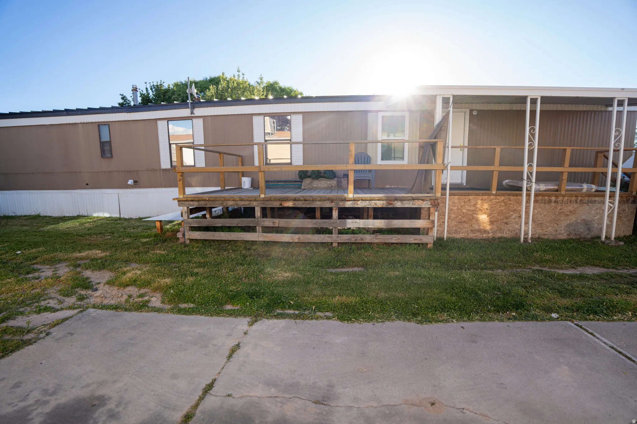 Exterior featuring a wood deck with railing, a covered entrance, and a concrete pad