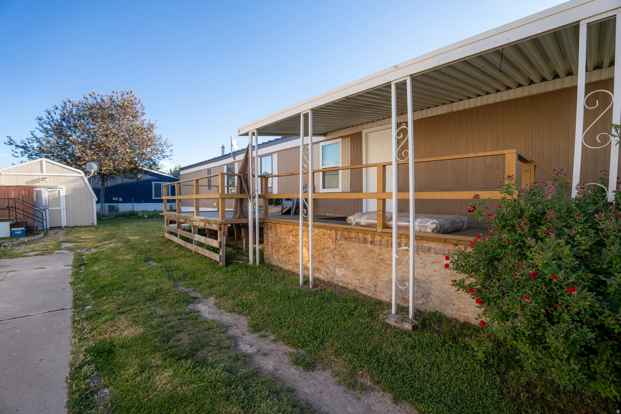 Exterior featuring a covered porch with white support posts, wood railing, and tan siding