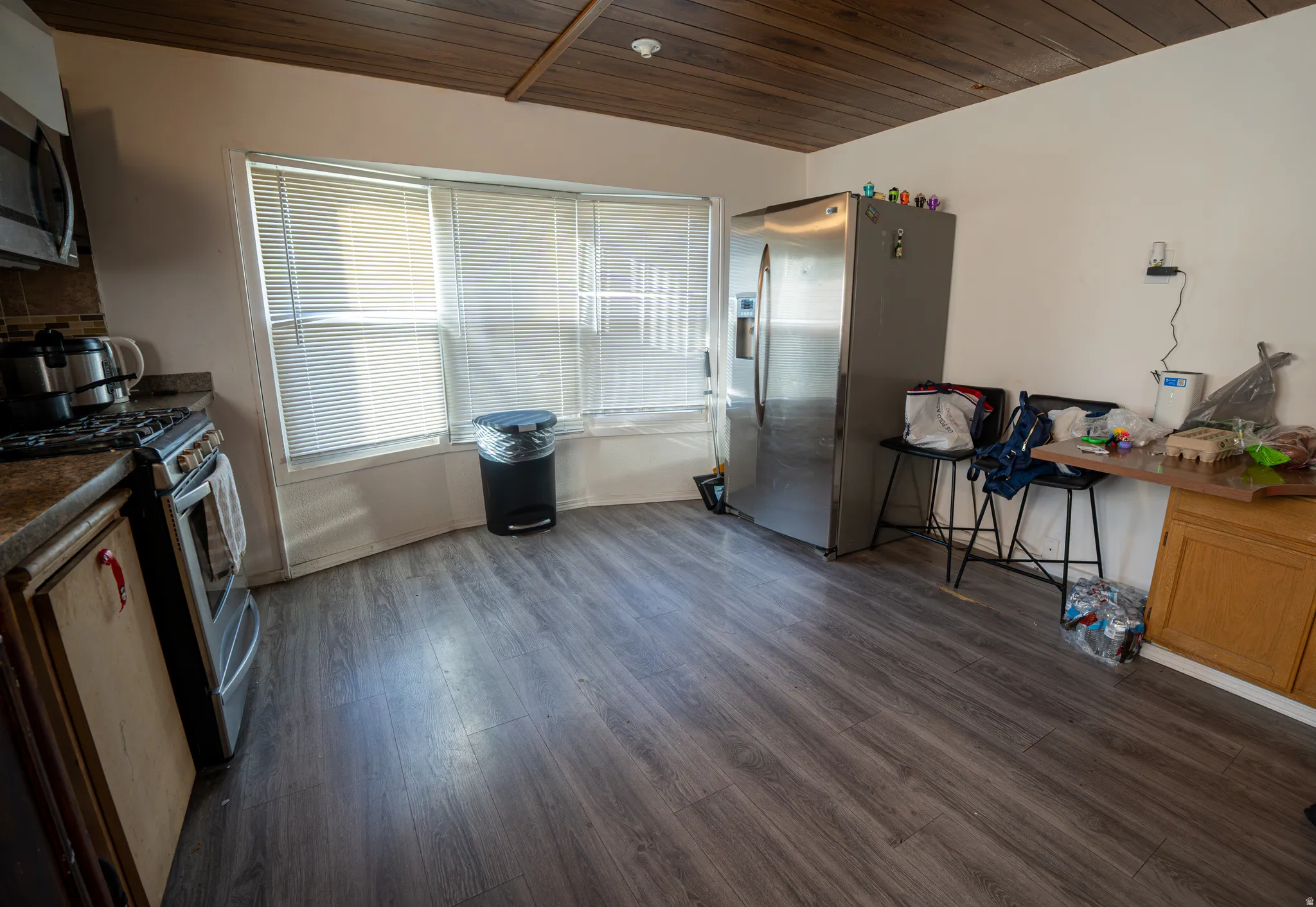 Kitchen area featuring dark wood-finish flooring, a stainless steel refrigerator, and a built-in oven with gas range