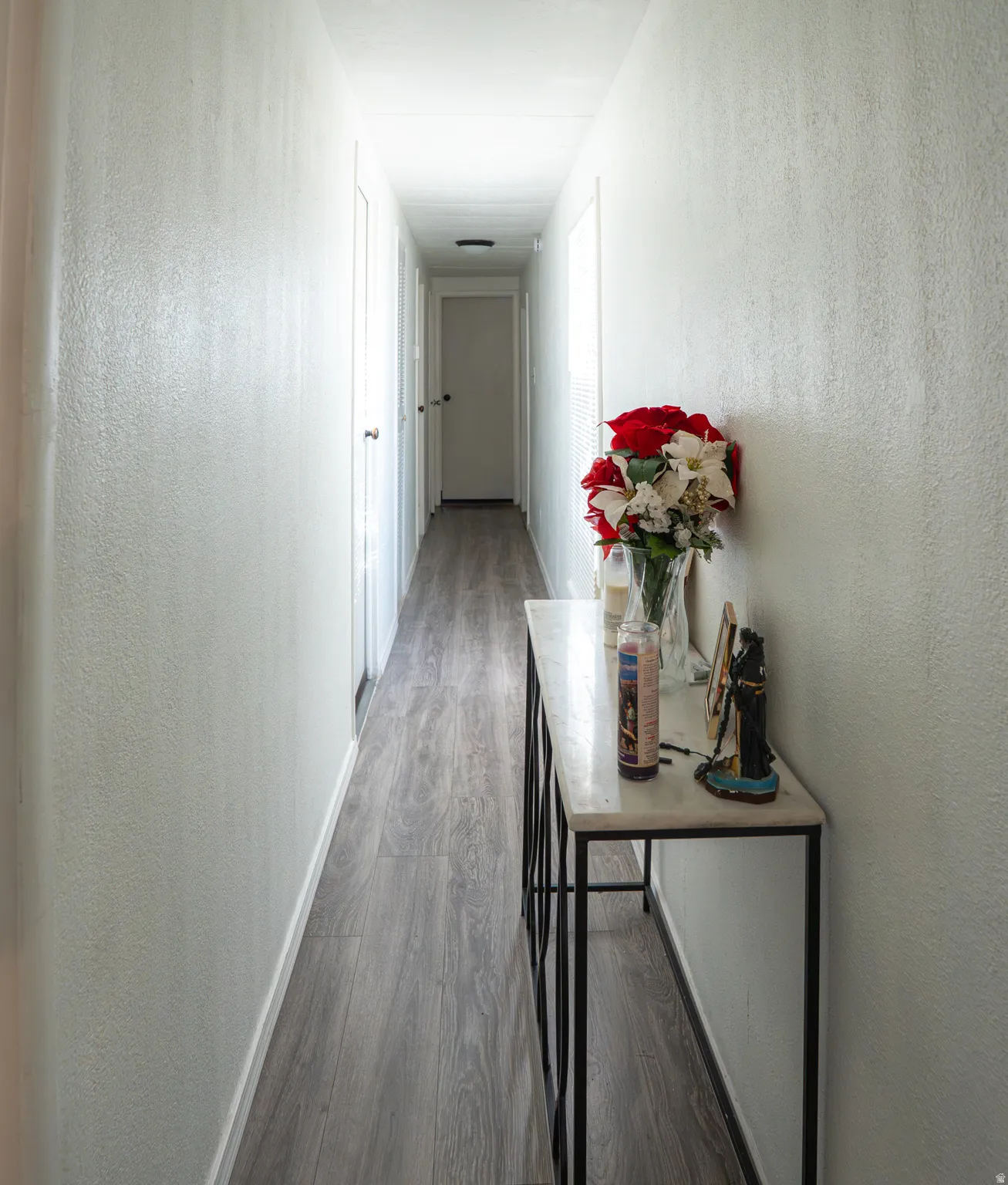 Long hallway featuring wood-finish flooring, white walls, and recessed lighting