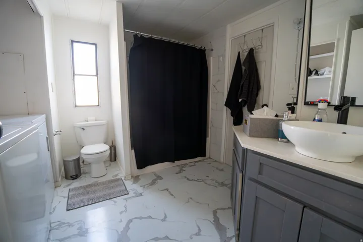 Bathroom featuring a vessel sink atop a gray vanity with a light-colored countertop