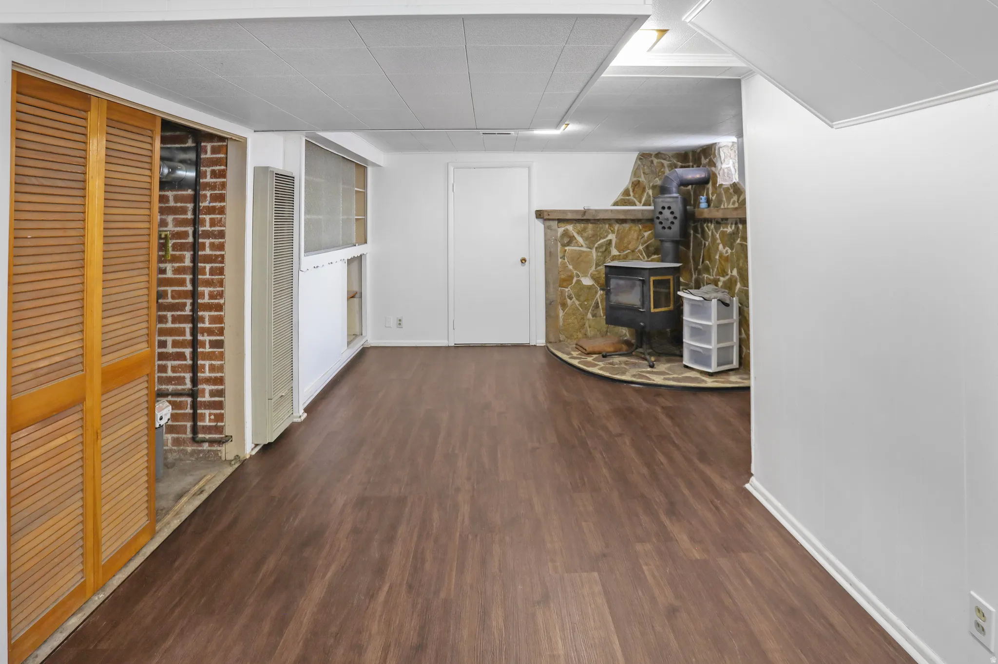 Wood-finish flooring throughout, featuring a stone-clad hearth with a wood-burning stove