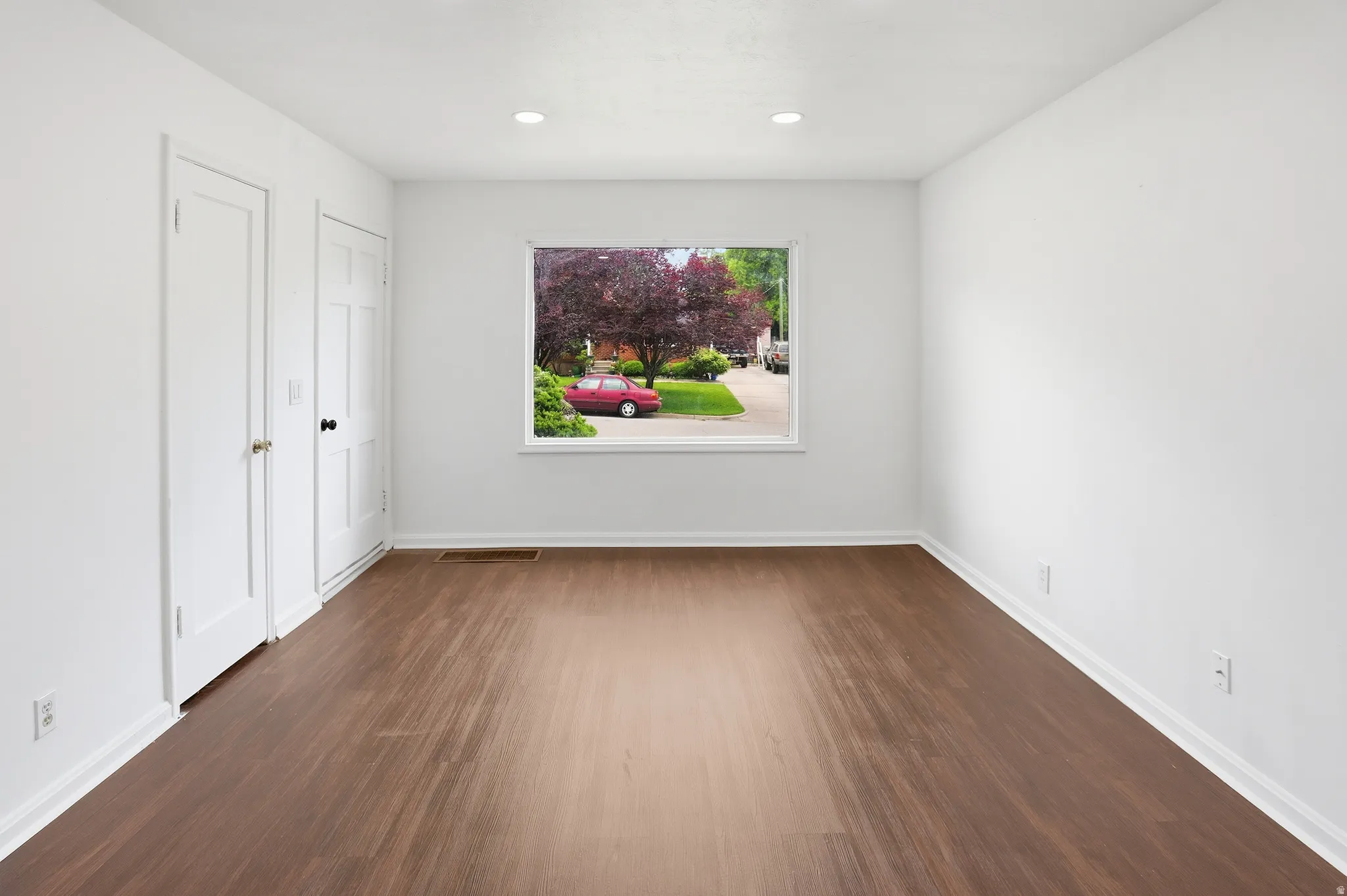 Spacious room featuring wood-finish flooring and bright white walls