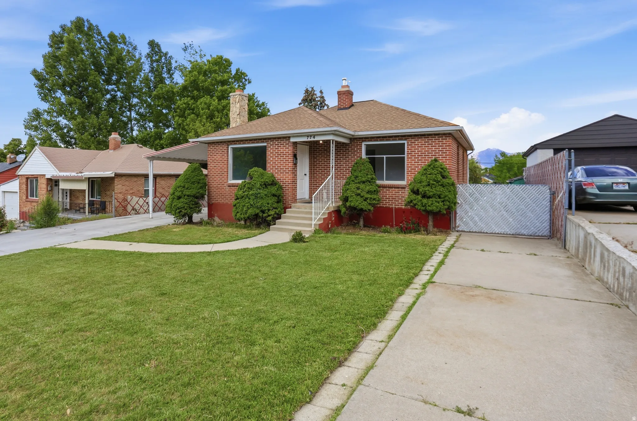 Brick exterior featuring a front lawn, paved driveway, and established landscaping