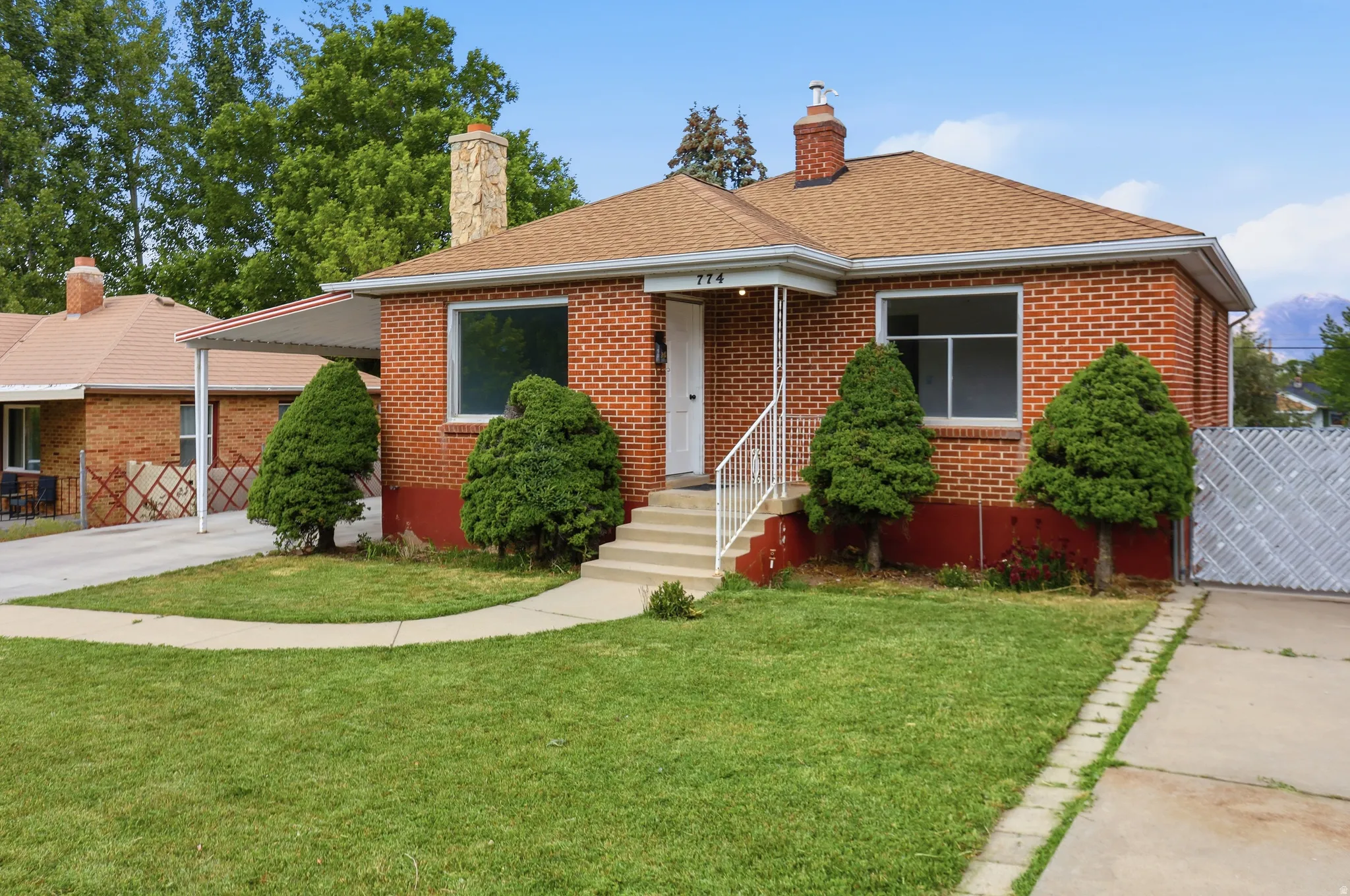 Brick-clad exterior with a gable roof, stone chimney, and covered carport