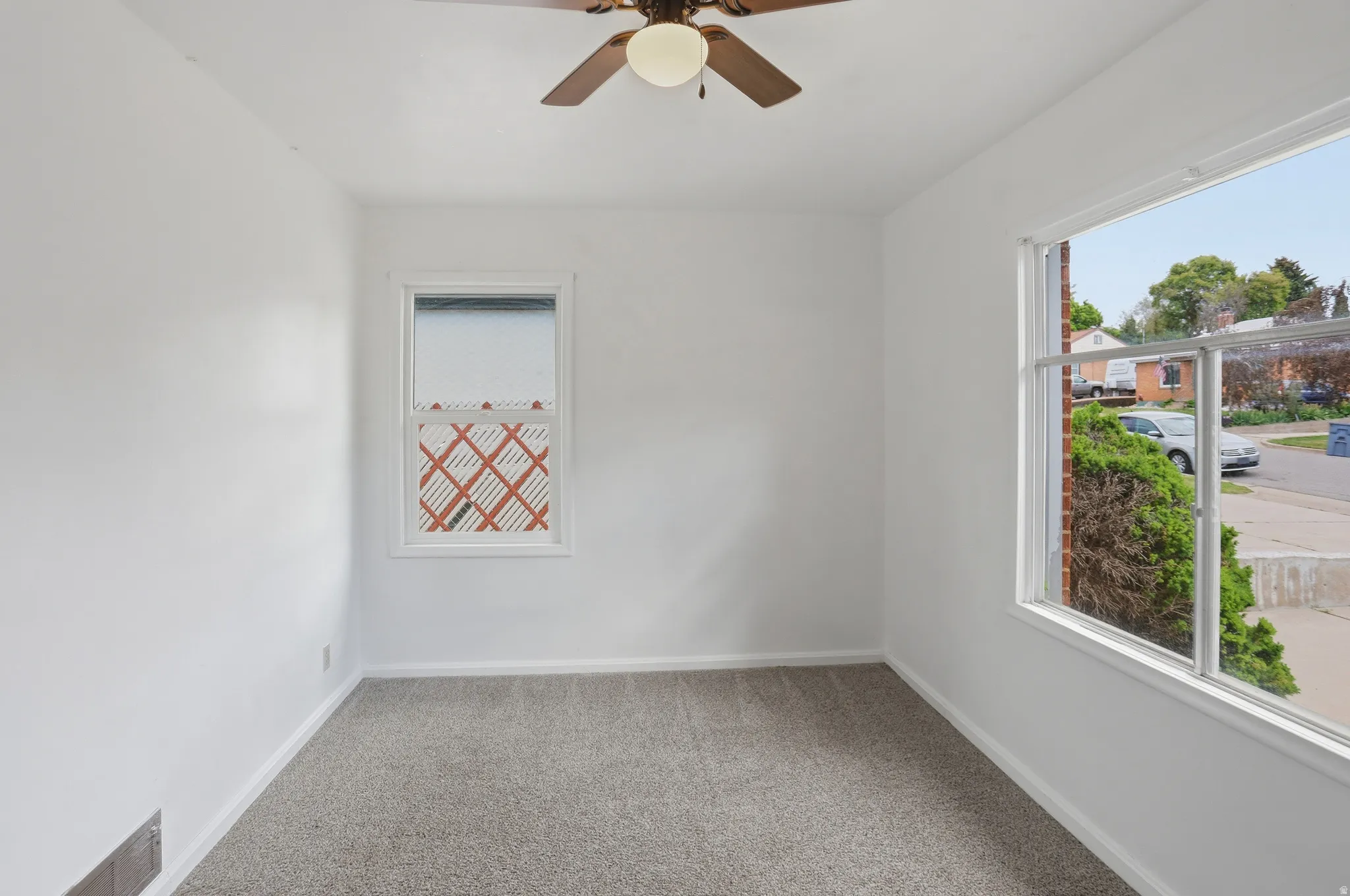 Room featuring neutral carpeting, white painted walls, and a ceiling fan with integrated lighting