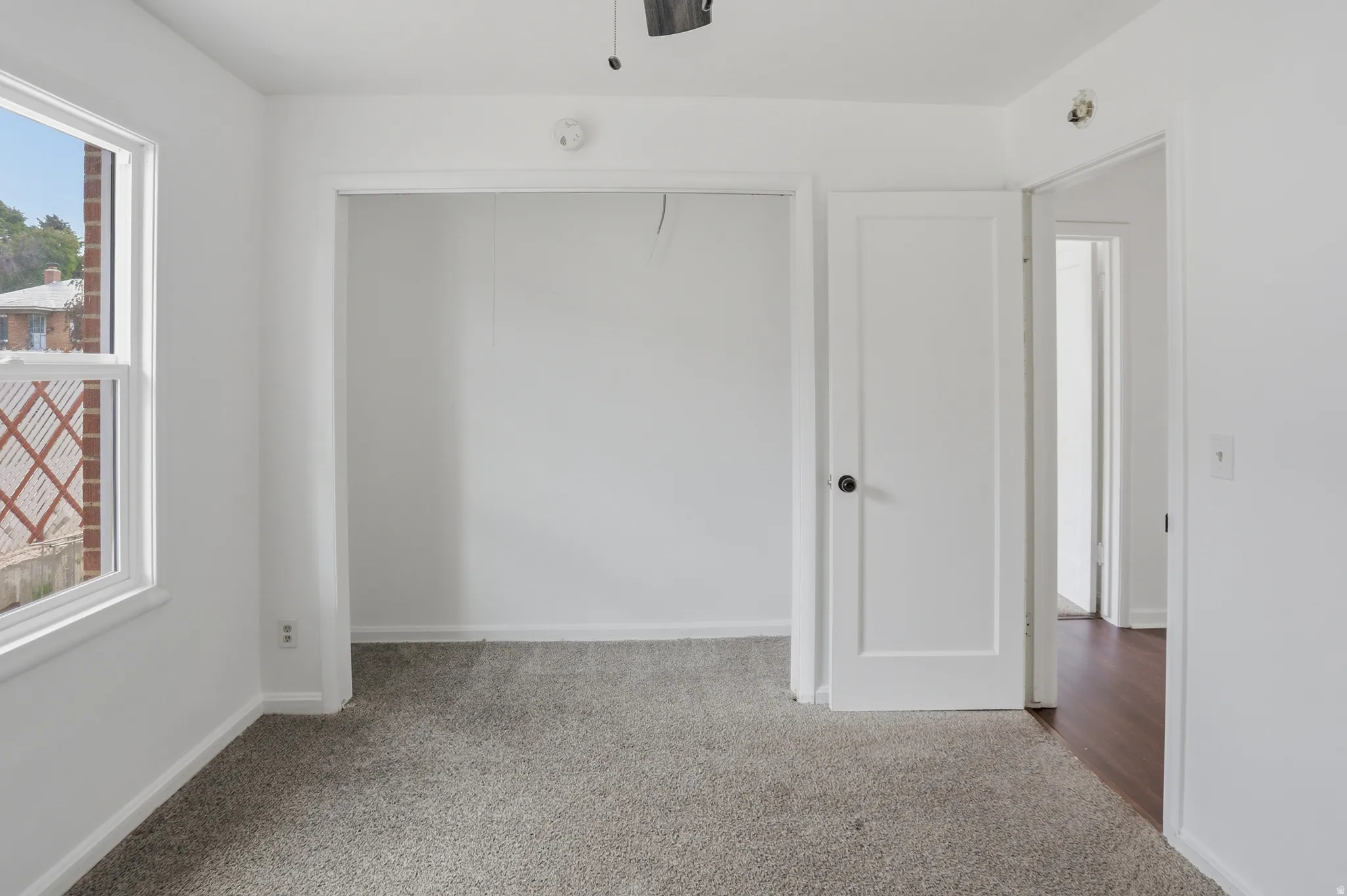 Room featuring neutral-toned carpeting, white walls, and a window with white trim