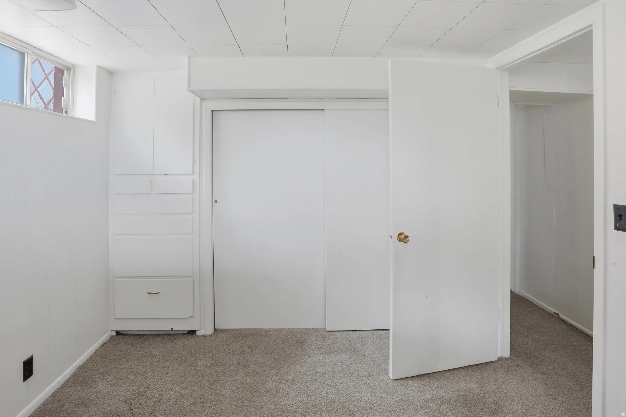 Carpeted flooring throughout, white painted walls, and a white drop ceiling