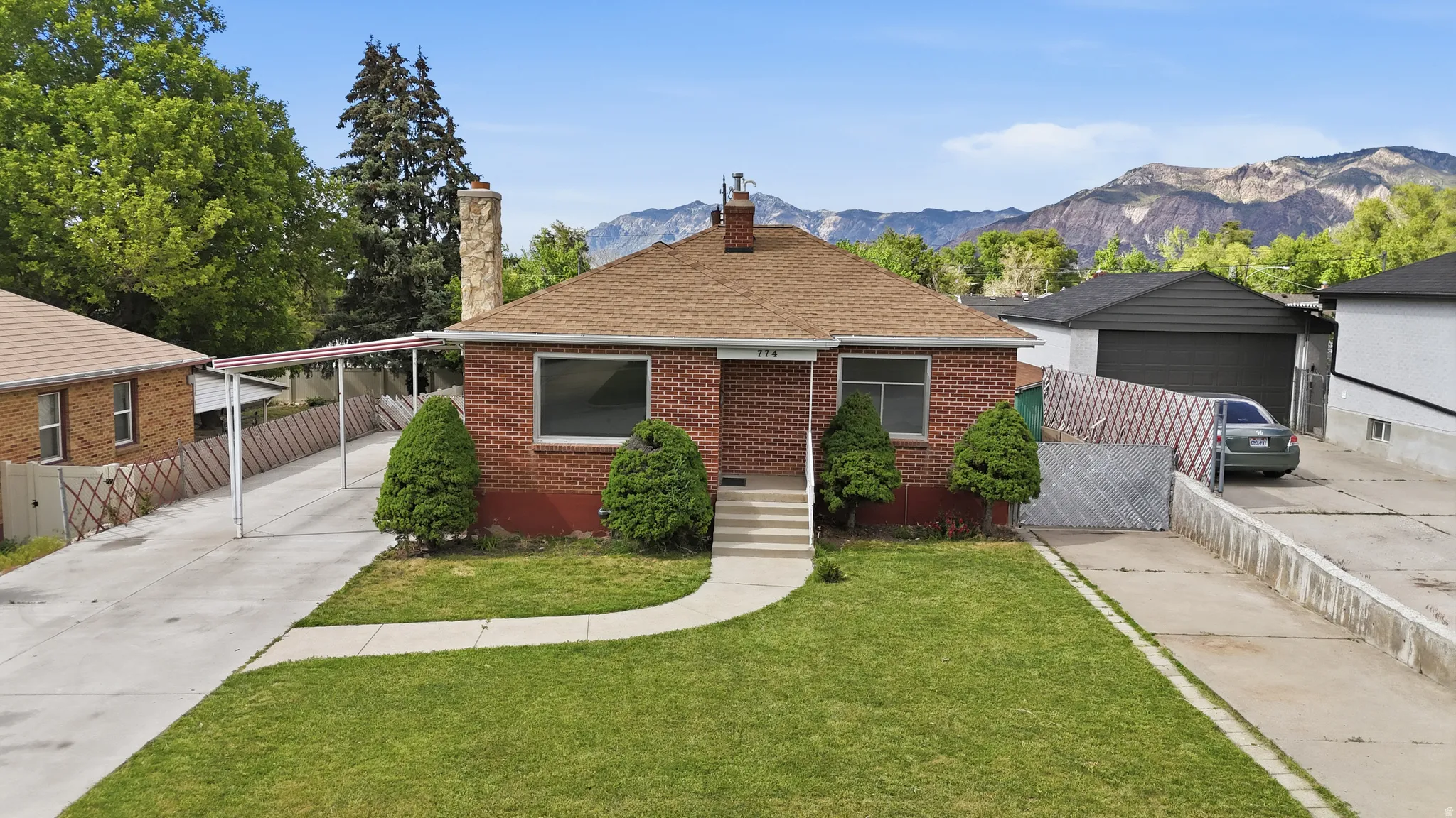 Brick exterior residence featuring a brown shingle roof and a front lawn