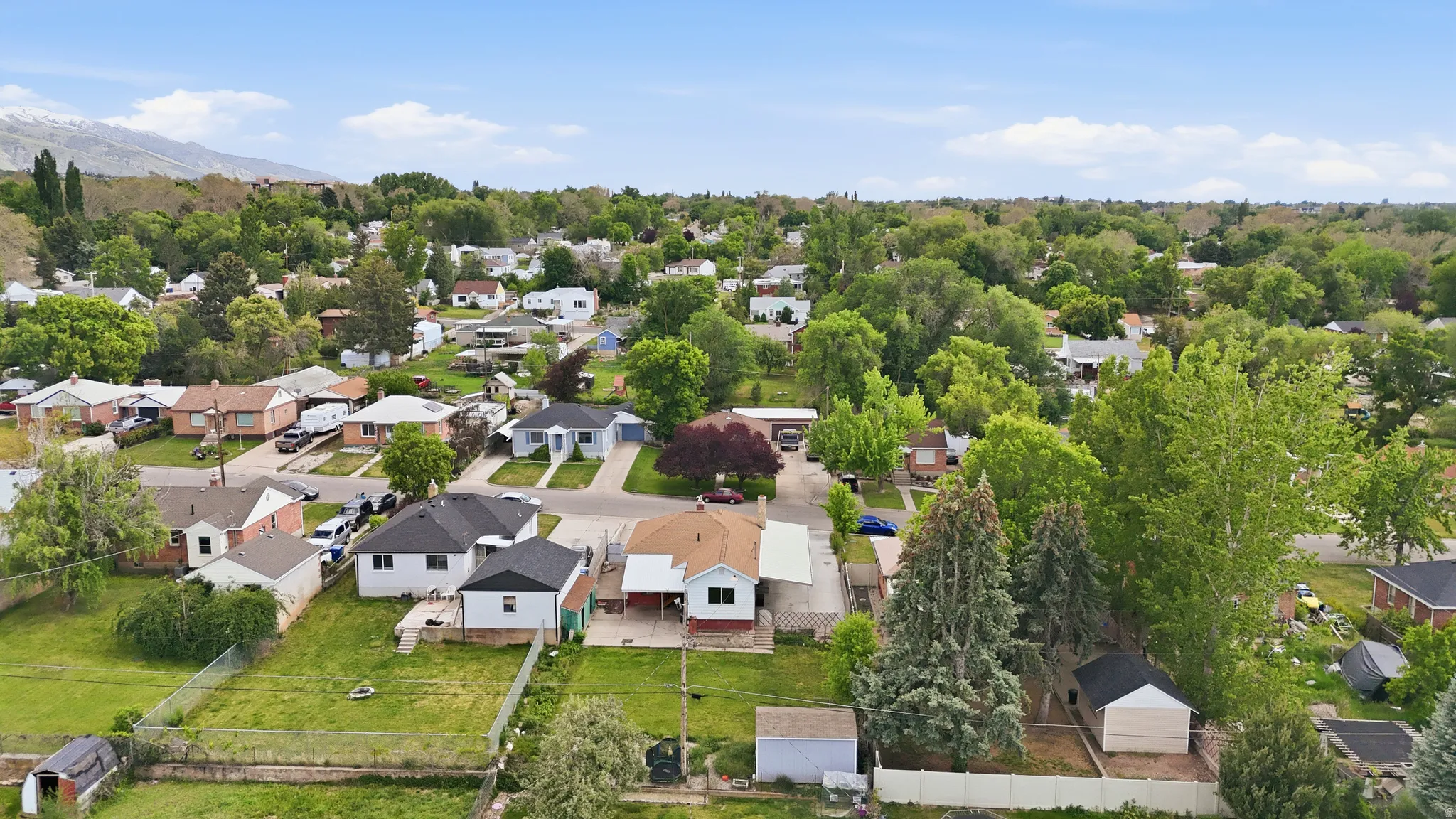 Aerial community perspective featuring residential properties, mature trees, and mountainous terrain in the distance