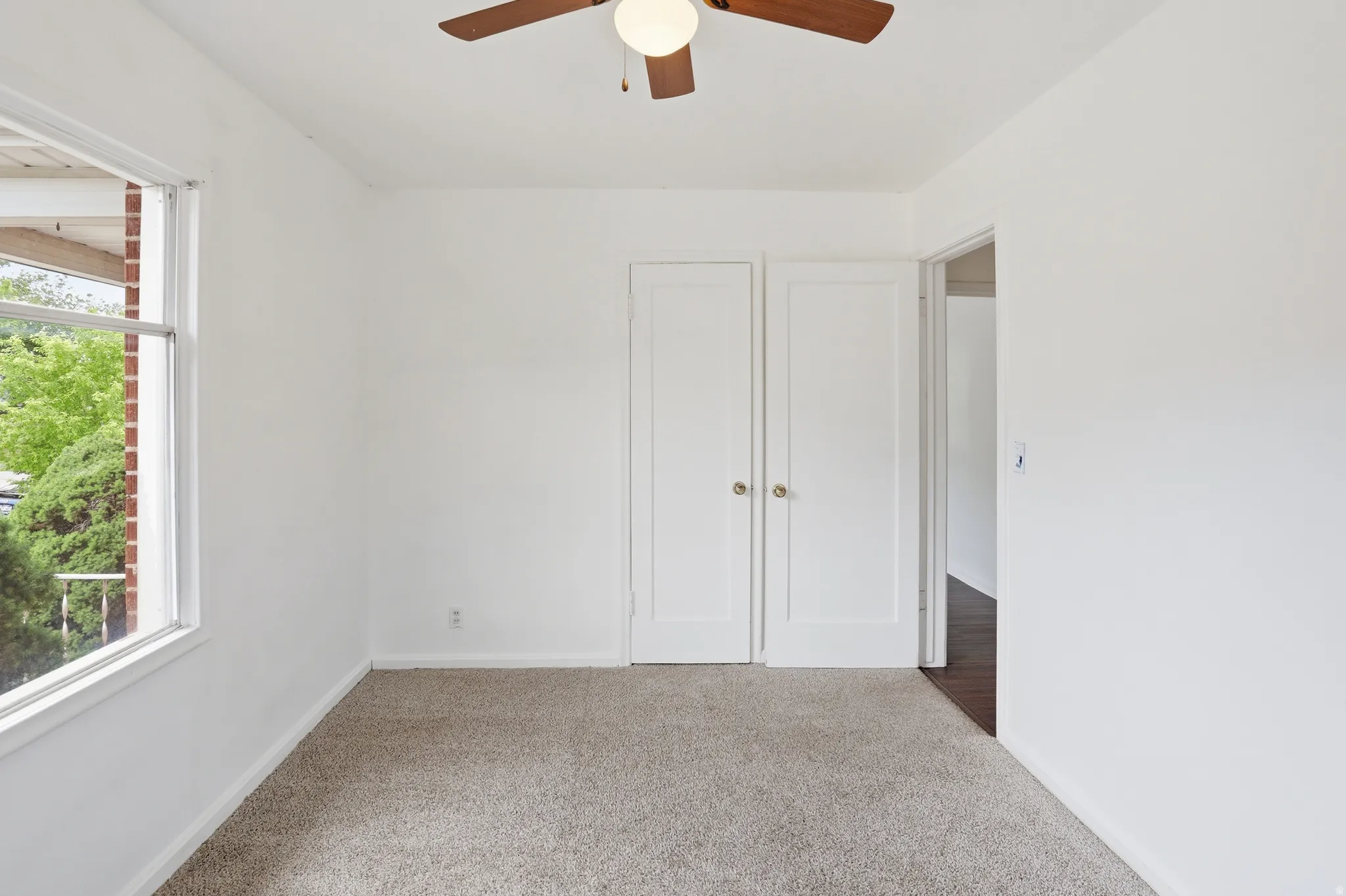 Neutral-toned carpeting paired with white walls, featuring a ceiling fan with integrated lighting