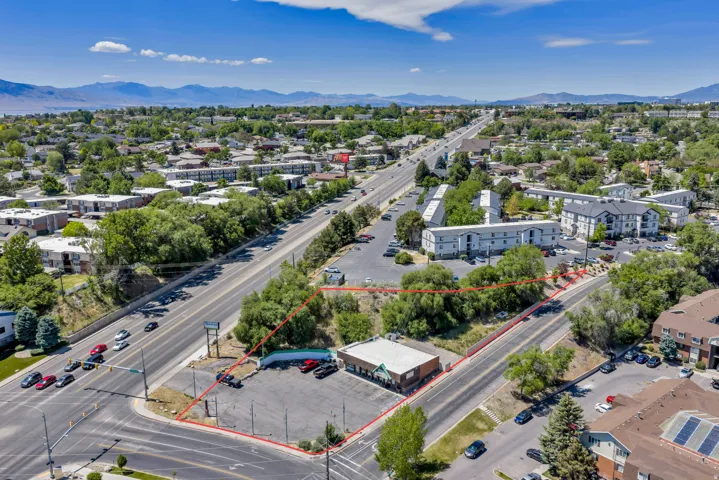 Aerial overview of a commercial property with an existing single-story building and an expansive paved parking area