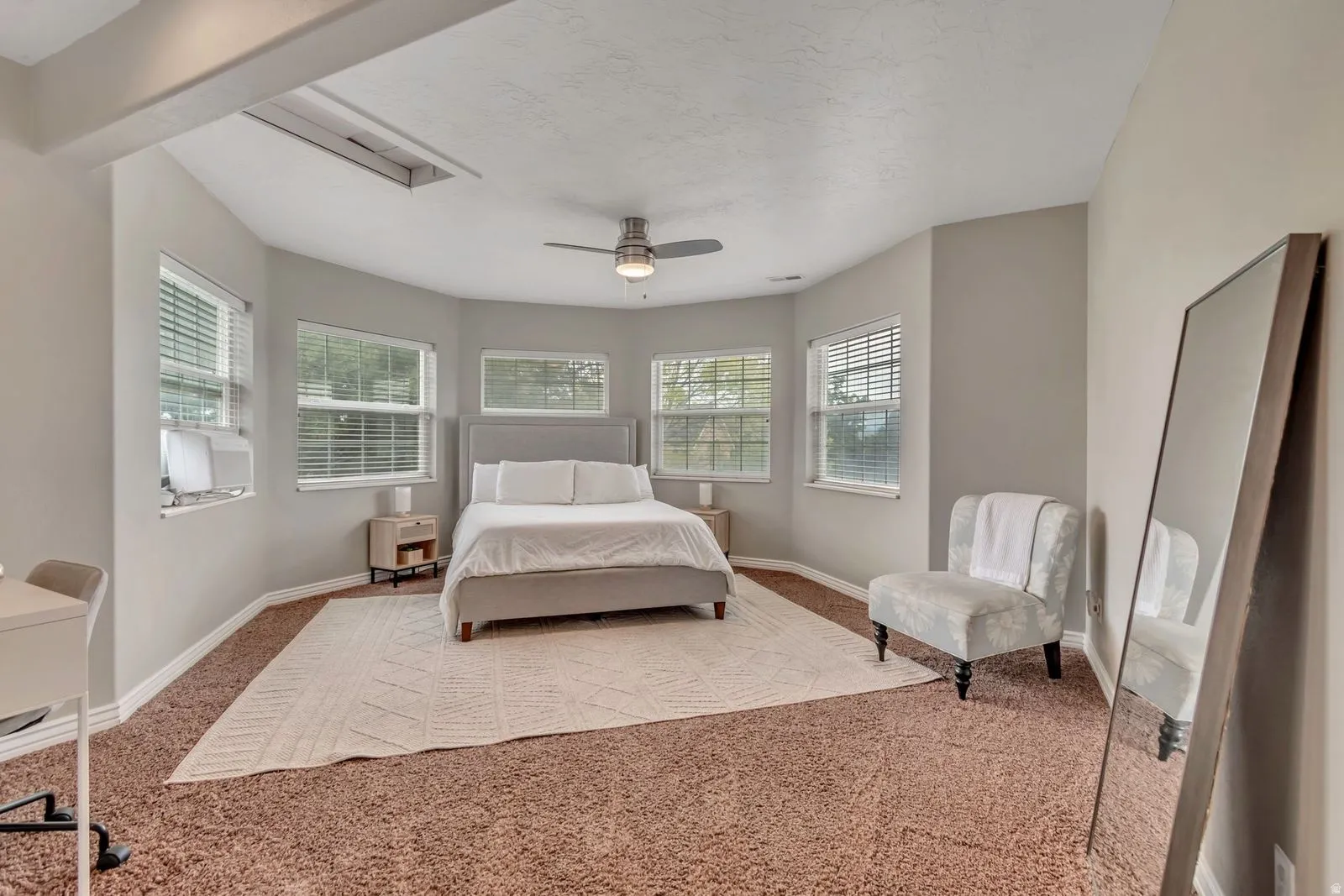 Spacious room featuring multiple windows with blinds, a ceiling fan, and carpeted flooring
