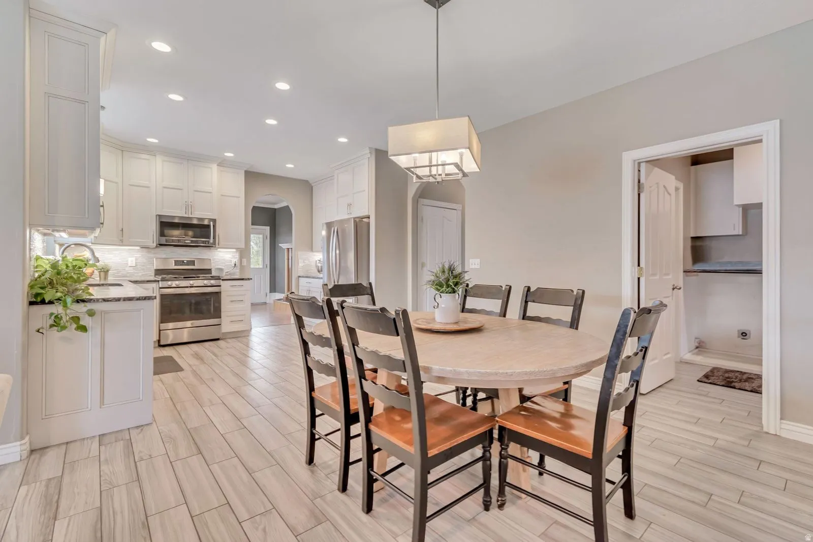 Open-concept dining area with wood-finish flooring, a contemporary chandelier, and recessed lighting