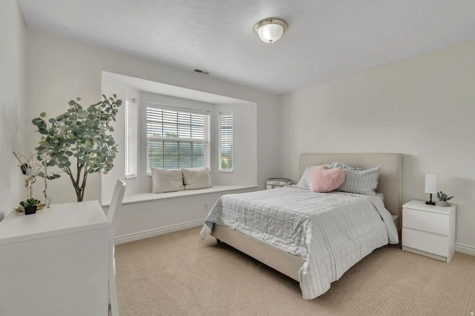 Light-filled room featuring a broad bay window with a built-in window seat, carpet flooring, and a flush-mount ceiling light fixture