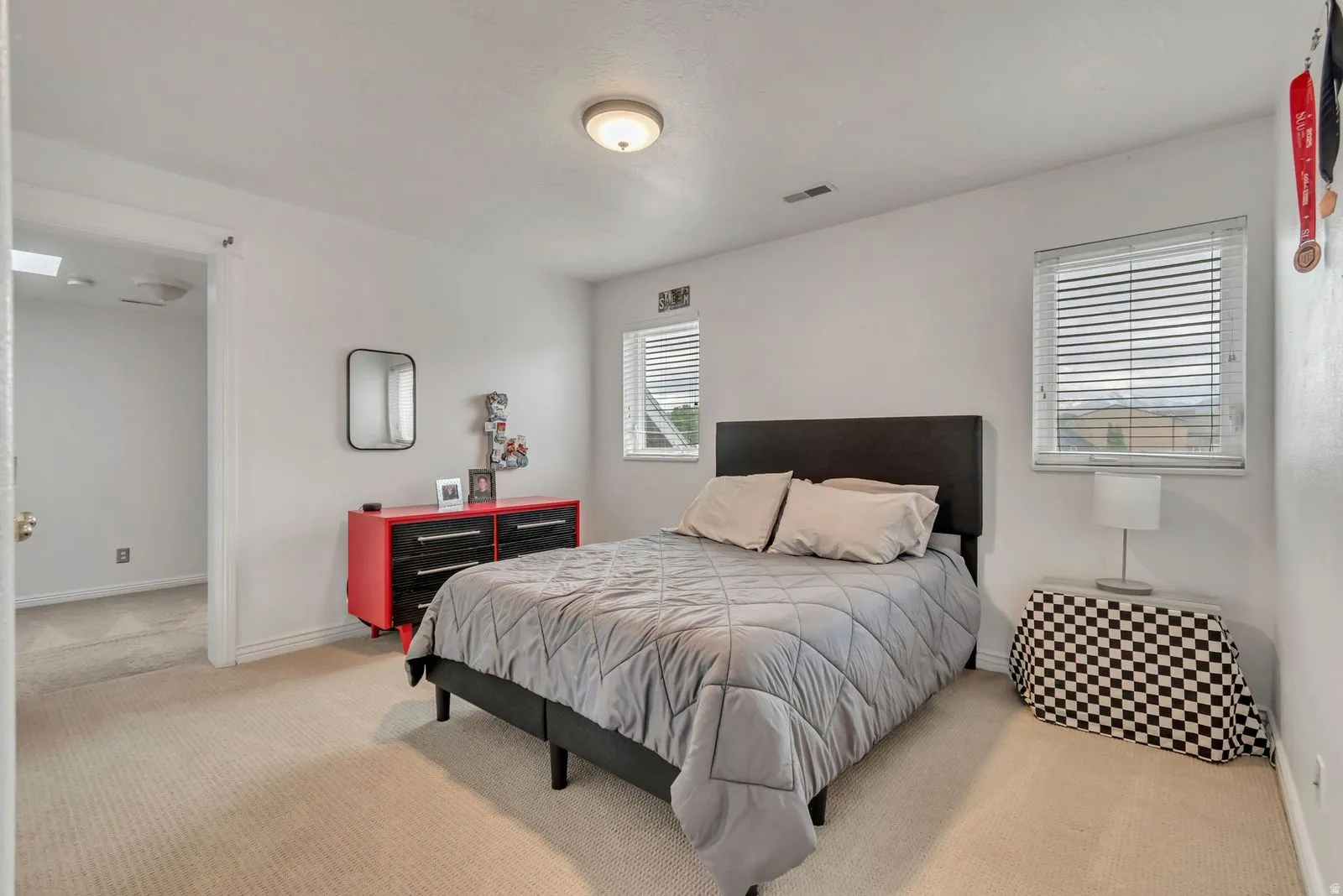 Carpeted room with white walls, two windows featuring blinds, and a flush-mount ceiling light fixture