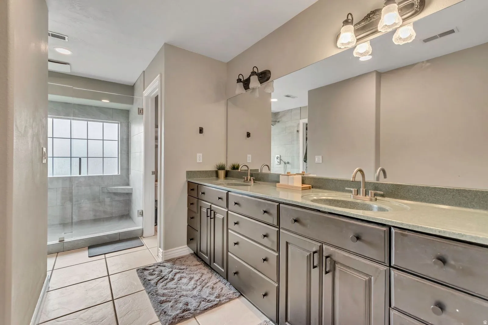 Spacious bathroom featuring a dual vanity with undermount sinks, contemporary cabinetry, and an expansive mirror