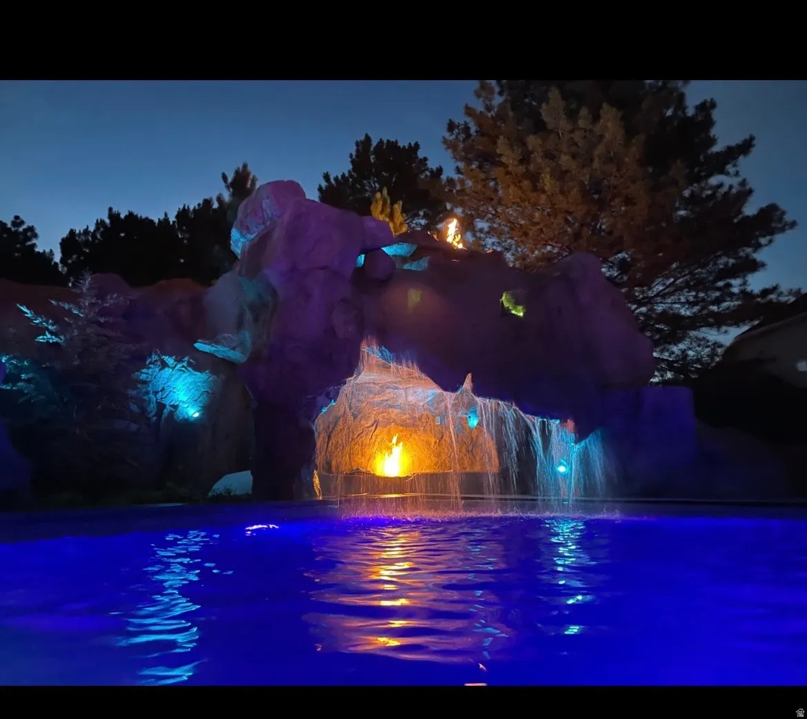 Custom grotto with integrated waterfalls, fire feature, and vibrant blue pool lighting