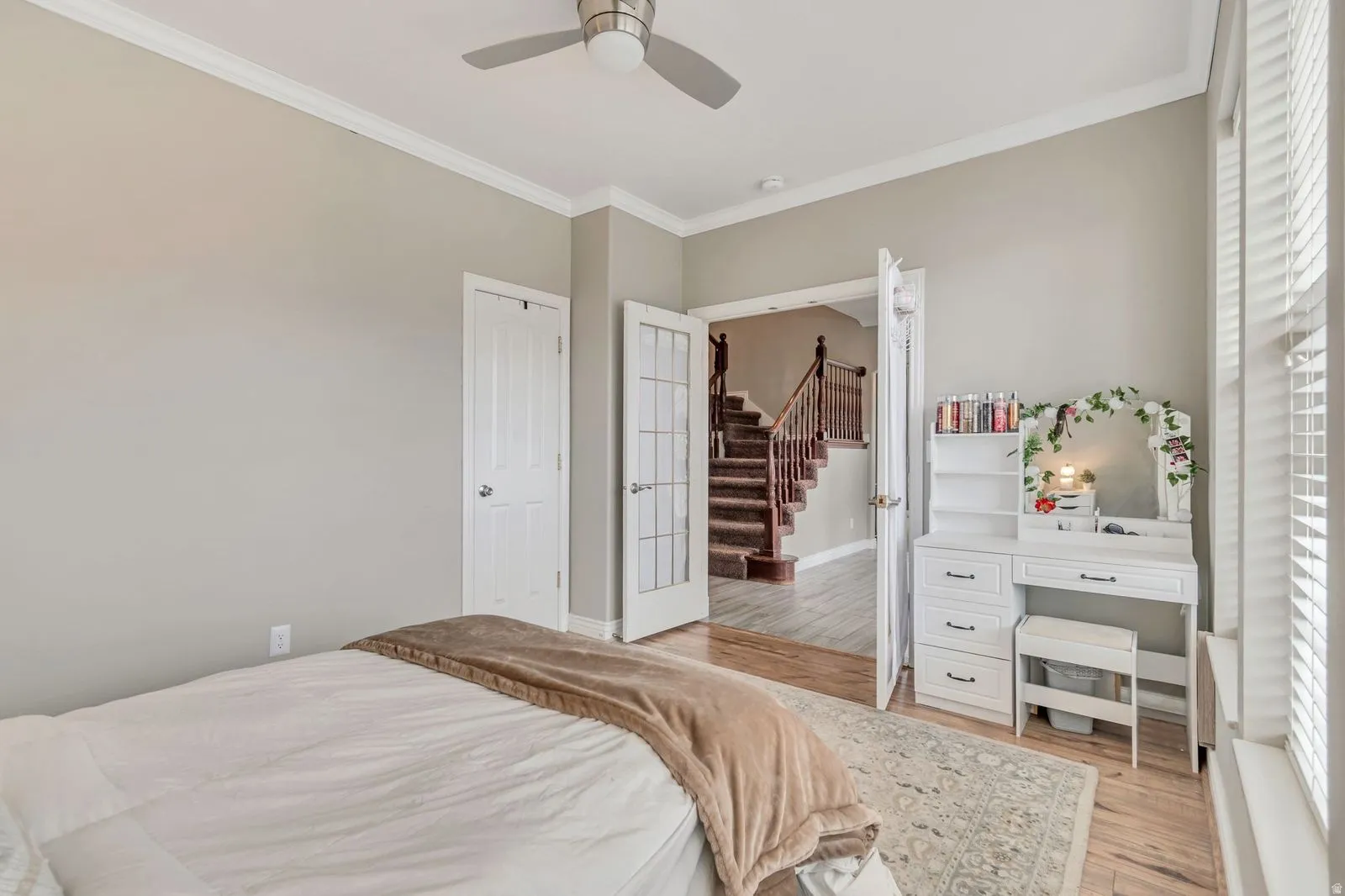 Interior room featuring crown molding, neutral wall tones, wood-finish flooring, a ceiling fan, and white window blinds