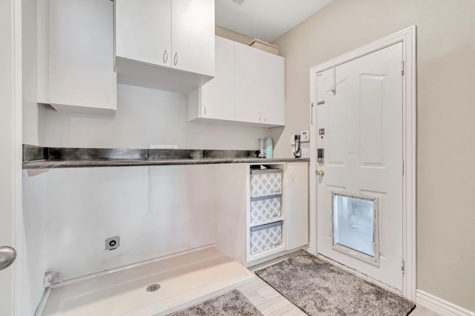 Utility room featuring white cabinetry, a dark countertop, a built-in shelving unit, and an exterior door