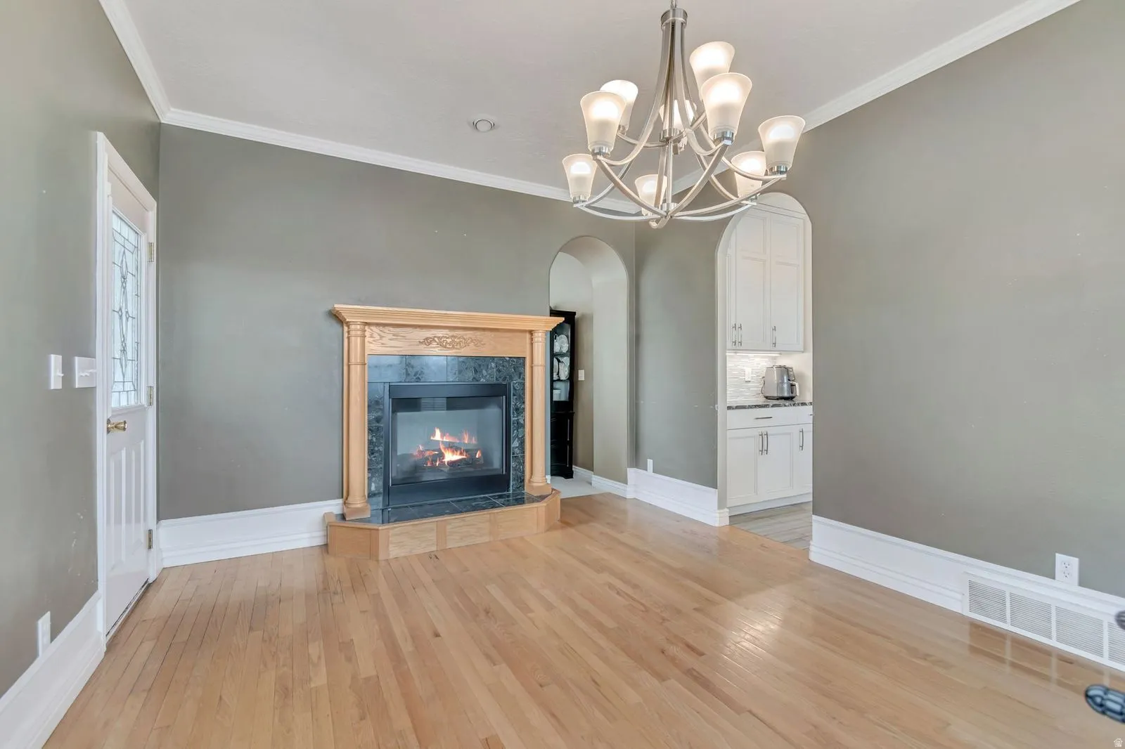 Hardwood flooring throughout this room featuring a corner fireplace with a stone surround and wood mantel
