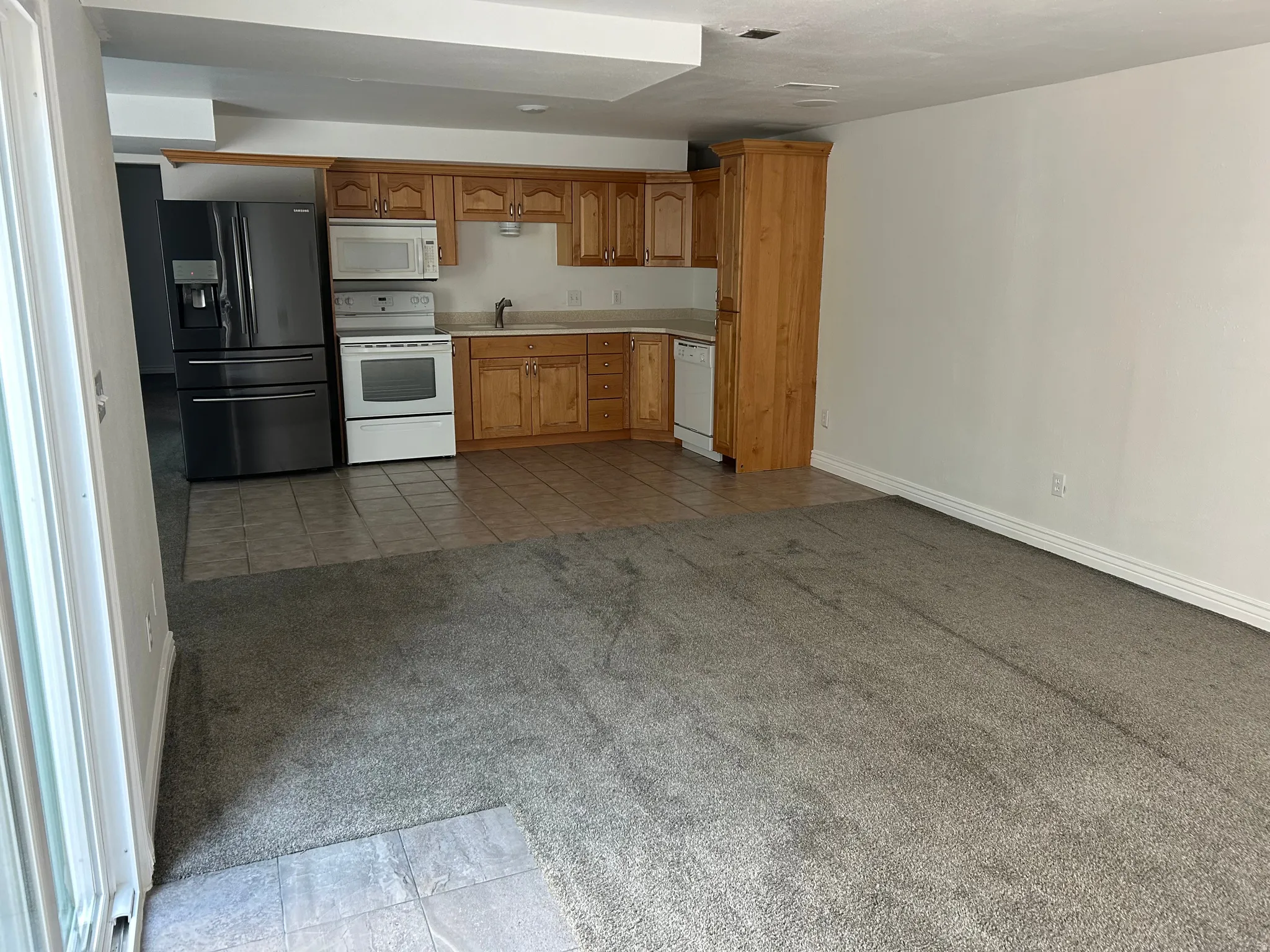 Kitchen area featuring light wood cabinetry, white appliances, and a dark stainless steel refrigerator