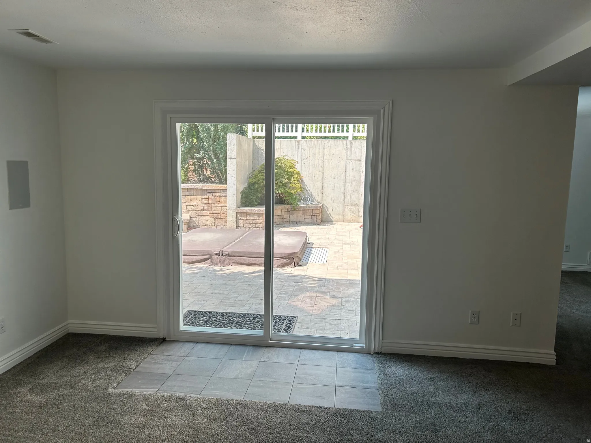 Sliding glass door opens to a paver patio with a stone retaining wall