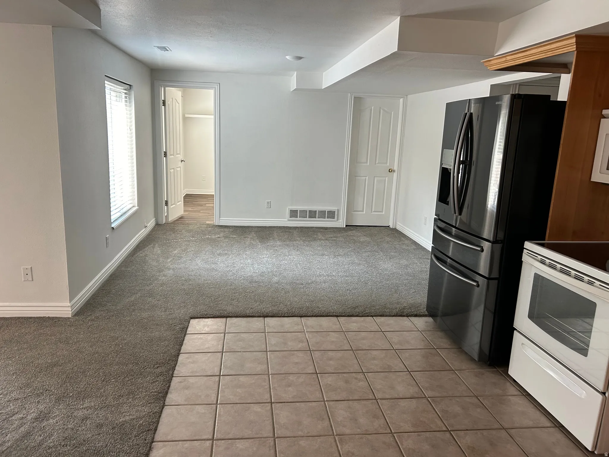 Open concept living area with mixed flooring, including carpet and square tile