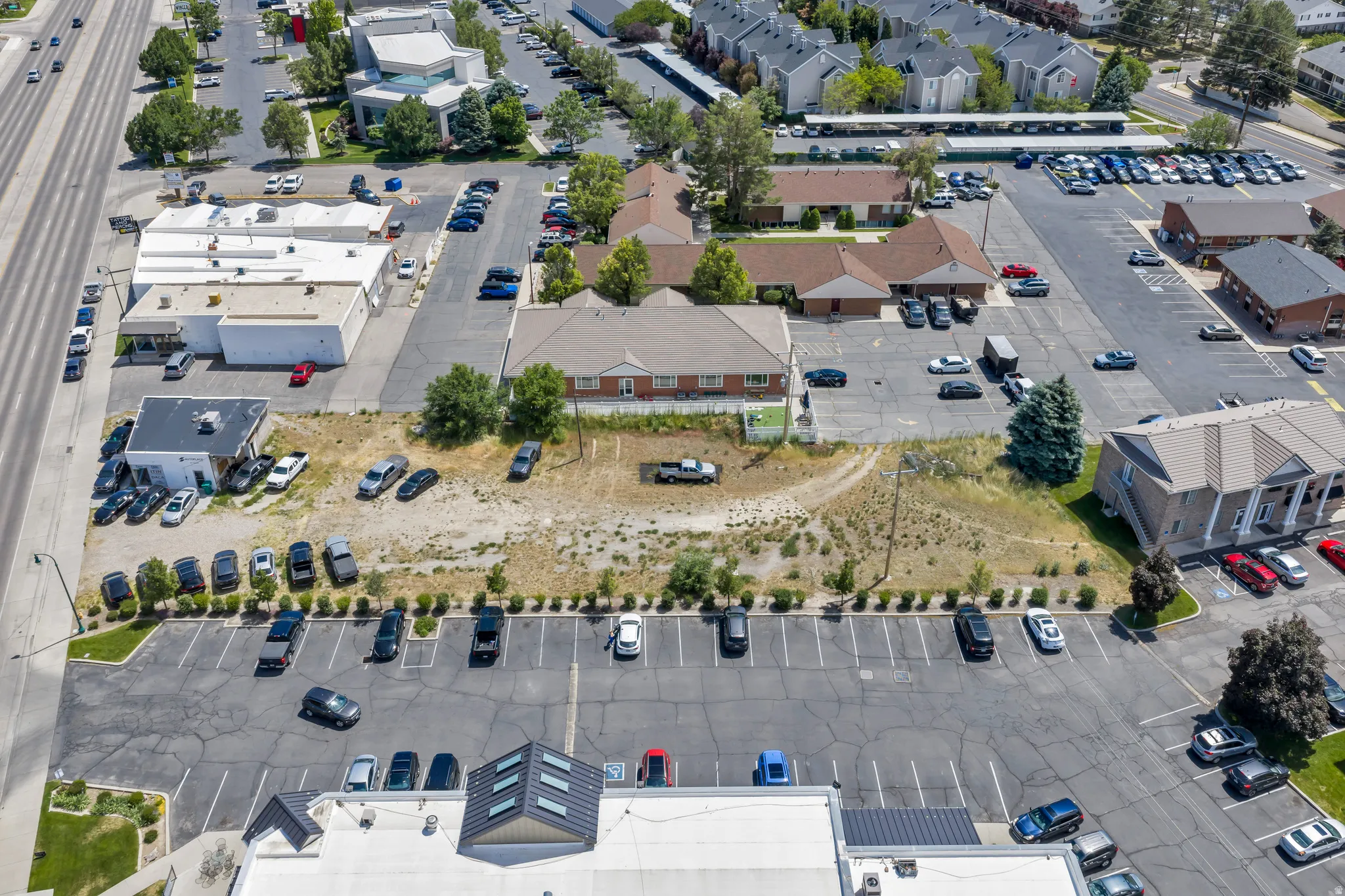 Expansive commercial property featuring multiple structures, extensive paved parking, and direct street frontage