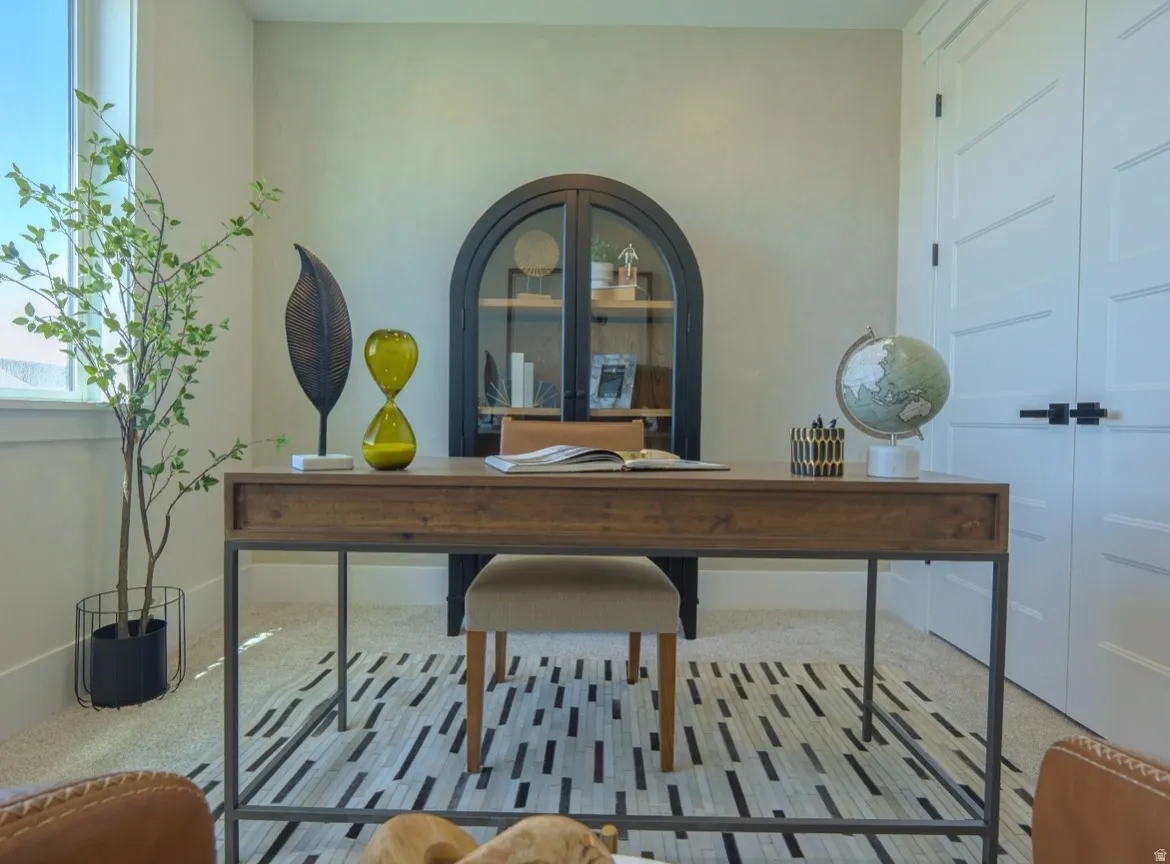 Dedicated interior space featuring light wall paint, carpet flooring, a large window, white paneled doors with black hardware, and a built-in arched display cabinet