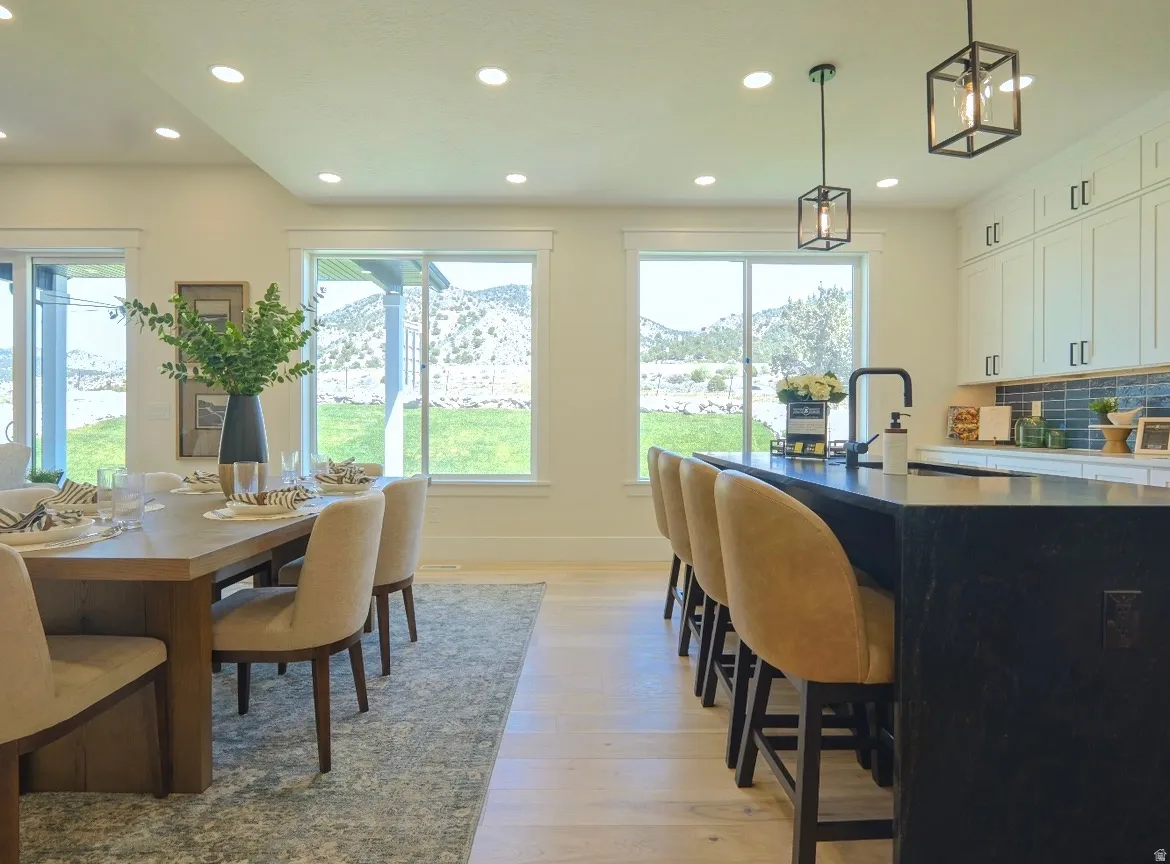 Open-concept kitchen and dining area featuring light wood-finish flooring, recessed lighting, and a large dining table