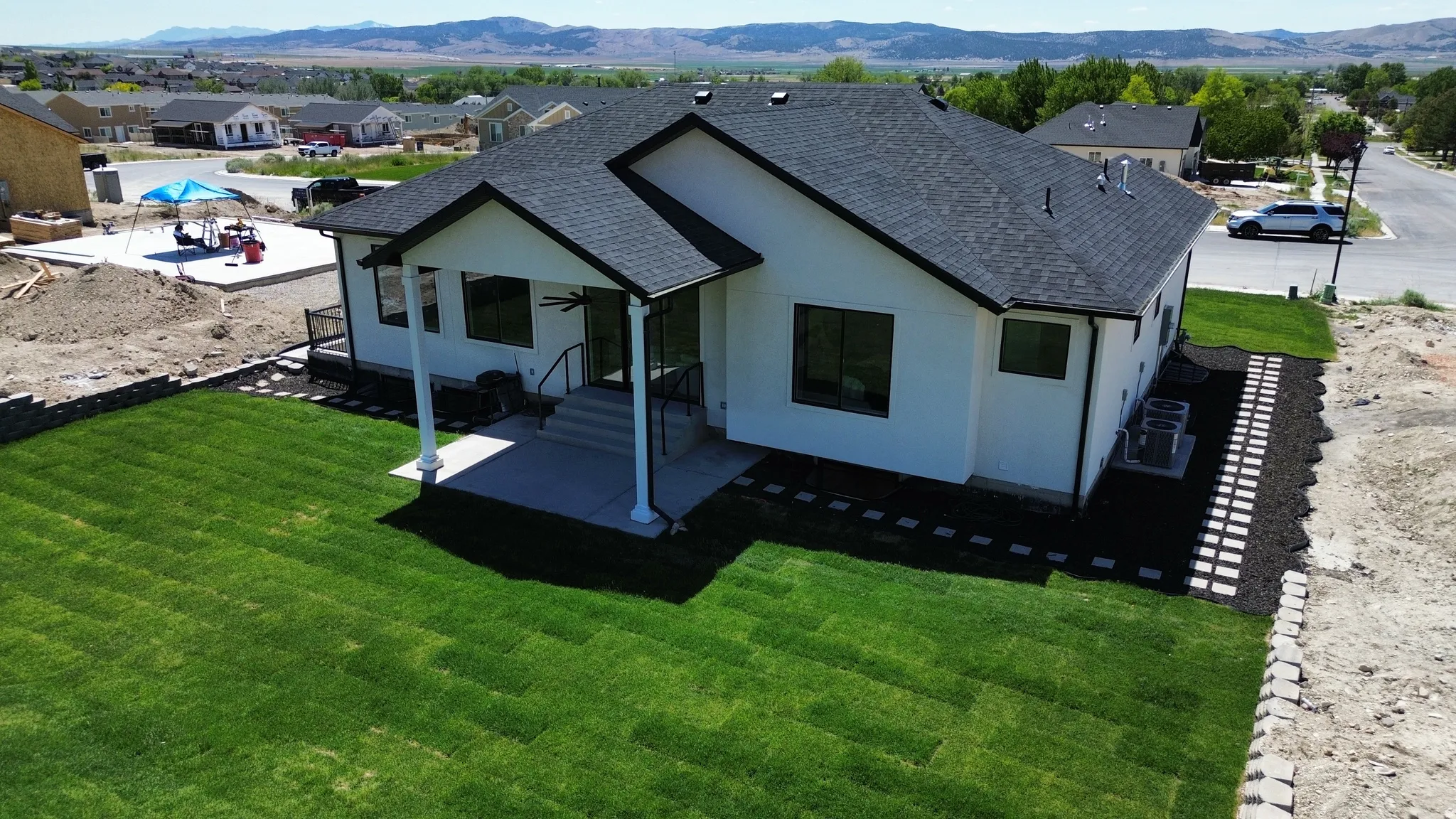 Expansive green lawn with a covered patio featuring white columns and a ceiling fan