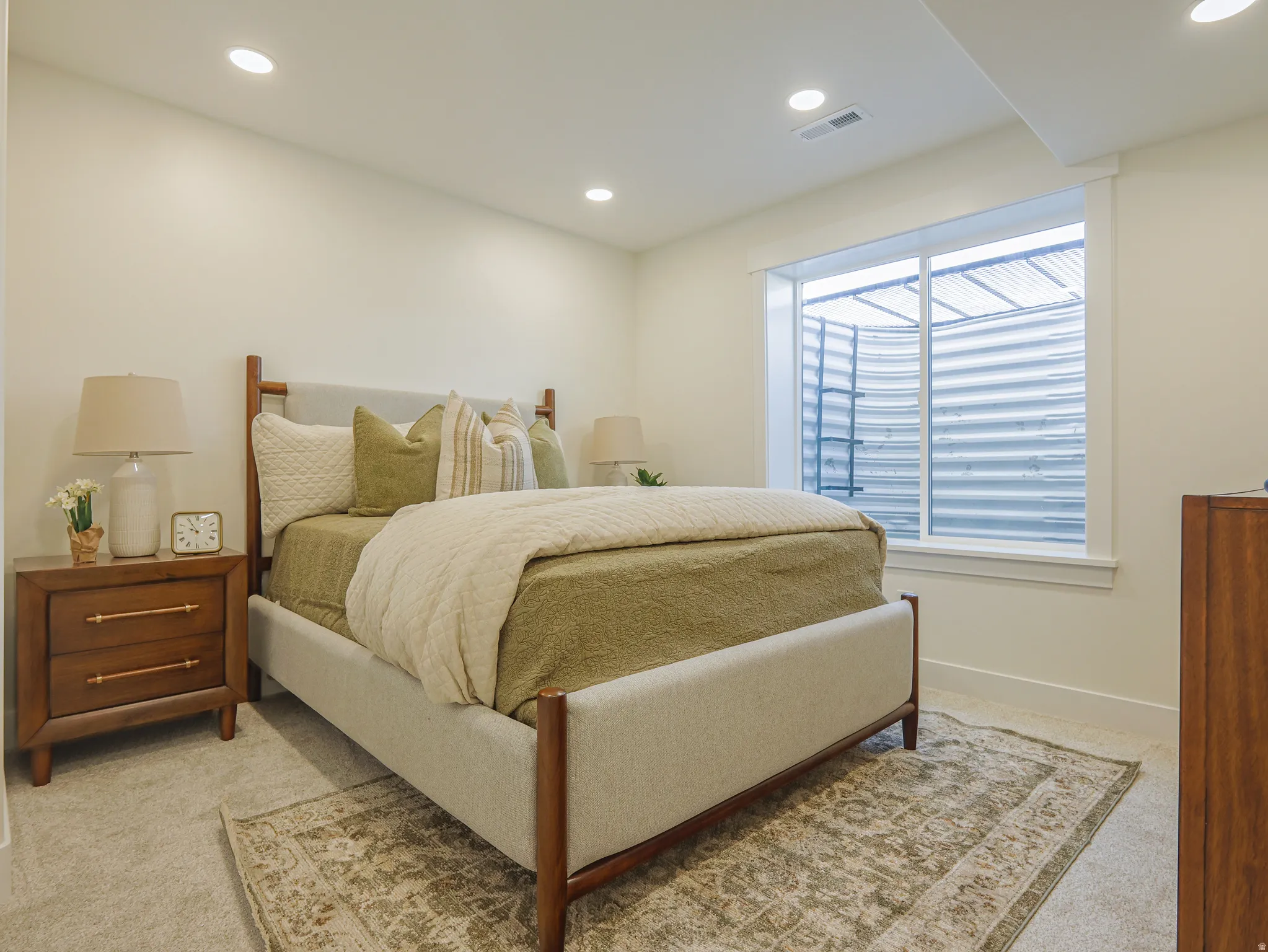 Carpeted room featuring a large egress window with white trim, recessed lighting, and light-toned walls